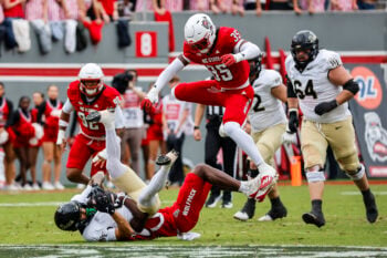 Oct 10, 2026; Raleigh, North Carolina, USA;  Wake Forest Demon Deacons wide receiver Carlos Hernandez (8) catches the ball while being jumped over by NC State Wolfpack linebacker LaCorian Hodge (35) during the first half of the game at Carter-Finley Stadium.  Mandatory Credit: Jaylynn Nash-Imagn Images