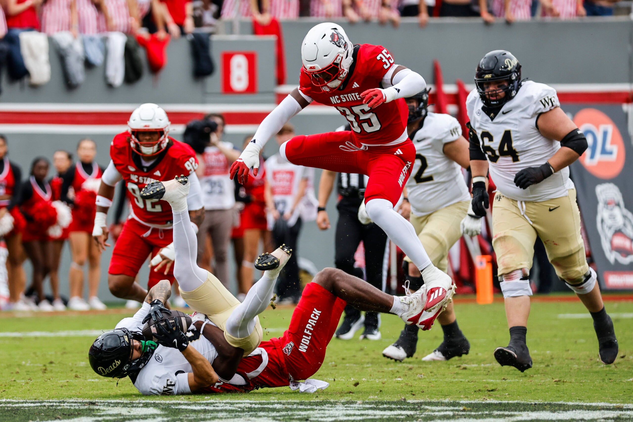 Oct 10, 2026; Raleigh, North Carolina, USA;  Wake Forest Demon Deacons wide receiver Carlos Hernandez (8) catches the ball while being jumped over by NC State Wolfpack linebacker LaCorian Hodge (35) during the first half of the game at Carter-Finley Stadium.  Mandatory Credit: Jaylynn Nash-Imagn Images