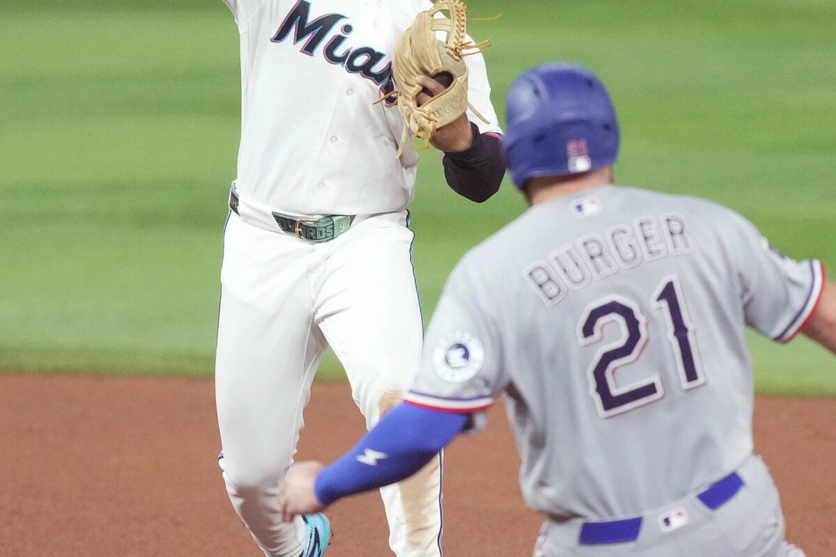 Jun 22, 2026; Miami, Florida, USA;  Miami Marlins second baseman Xavier Edwards (9) turns a double play as Texas Rangers Jake Burger (21) slides into second base at loanDepot Park. Mandatory Credit: Jim Rassol-Imagn Images