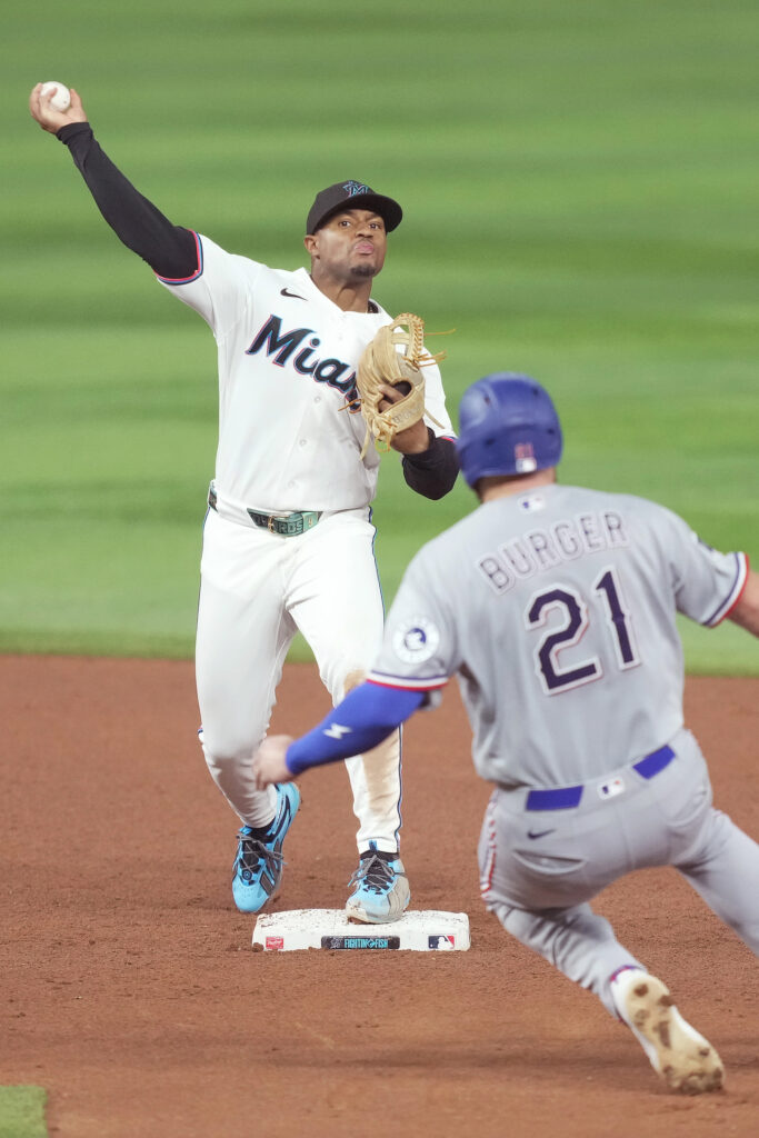 Jun 22, 2026; Miami, Florida, USA;  Miami Marlins second baseman Xavier Edwards (9) turns a double play as Texas Rangers Jake Burger (21) slides into second base at loanDepot Park. Mandatory Credit: Jim Rassol-Imagn Images