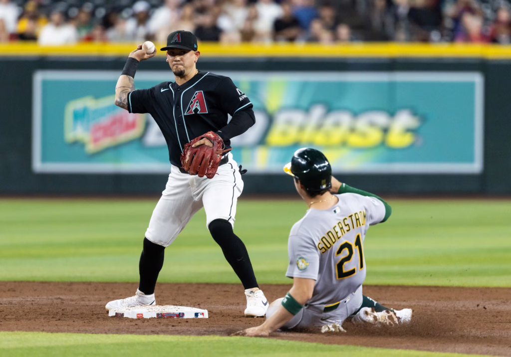 Jul 21, 2026; Phoenix, Arizona, USA; Arizona Diamondbacks second baseman Ildemaro Vargas (left) throws to first base to complete the double play after forcing out sliding Athletics base runner Tyler Soderstrom in the third inning at Chase Field. Mandatory Credit: Mark J. Rebilas-Imagn Images