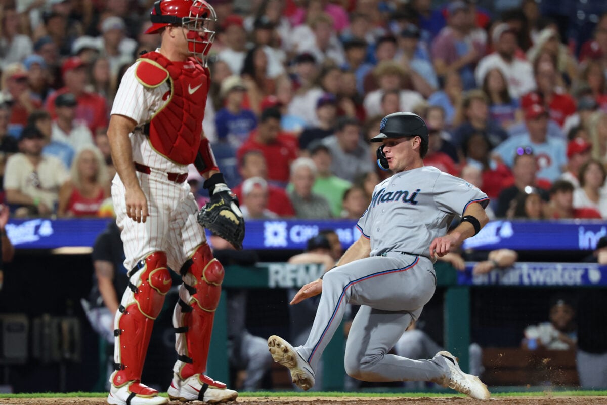 Aug 18, 2026; Philadelphia, Pennsylvania, USA; Miami Marlins right fielder Griffin Conine (18) scores past Philadelphia Phillies catcher J.T. Realmuto (10) during the eighth inning at Citizens Bank Park. Mandatory Credit: Bill Streicher-Imagn Images