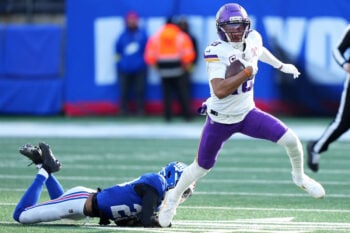 Dec 21, 2025; East Rutherford, New Jersey, USA; Minnesota Vikings wide receiver Justin Jefferson (18) makes a catch against New York Giants cornerback Paulson Adebo (21) during the first half at MetLife Stadium. Mandatory Credit: Robert Deutsch-Imagn Images