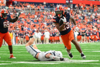Sep 5, 2026; Syracuse, New York, USA; Syracuse Orange running back Shavane Anderson Jr. (23) runs with the ball past the tackle attempt of New Hampshire Wildcats linebacker Trevor Barry (left) during the first half at the JMA Wireless Dome. Mandatory Credit: Rich Barnes-Imagn Images