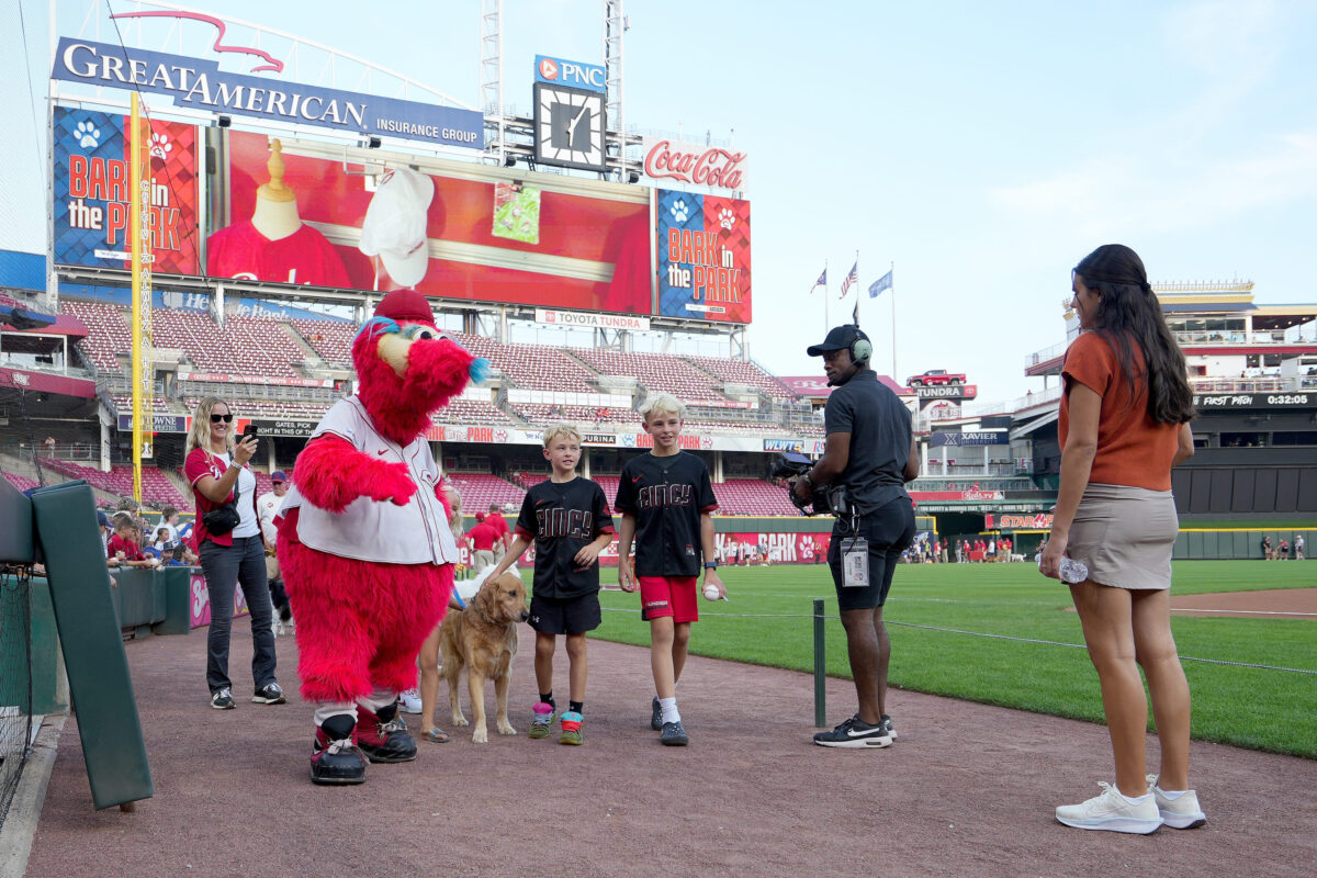 Fans walk the warning track with their dogs during the Bark in the Park event ahead of a baseball game between the Cincinnati Reds and Los Angeles Dodgers, Wednesday, Sept. 16, 2026, at Great American Ball Park in downtown Cincinnati.