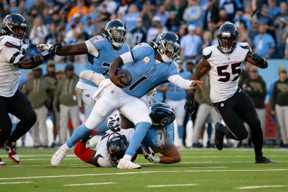 Nov 16, 2025; Nashville, Tennessee, USA;  Tennessee Titans quarterback Cameron Ward (1) stiff arms Houston Texans defensive tackle Mario Edwards Jr. (97) during the second half during the second half at Nissan Stadium. Mandatory Credit: Steve Roberts-Imagn Images