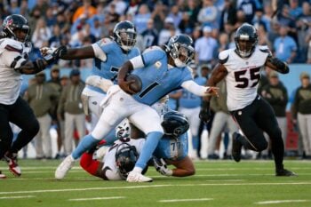 Nov 16, 2025; Nashville, Tennessee, USA;  Tennessee Titans quarterback Cameron Ward (1) stiff arms Houston Texans defensive tackle Mario Edwards Jr. (97) during the second half during the second half at Nissan Stadium. Mandatory Credit: Steve Roberts-Imagn Images