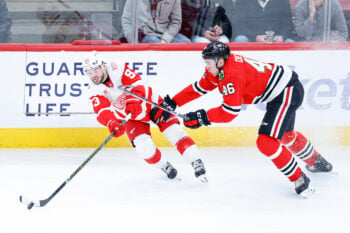 Dec 13, 2025; Chicago, Illinois, USA; Detroit Red Wings right wing Alex Debrincat (93) passes the puck against Chicago Blackhawks defenseman Louis Crevier (46) during the third period at United Center. Mandatory Credit: Kamil Krzaczynski-Imagn Images