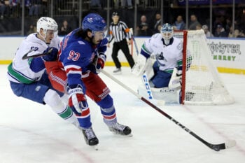 Dec 16, 2025; New York, New York, USA; New York Rangers center Mika Zibanejad (93) plays the puck against Vancouver Canucks defenseman Tyler Myers (57) during the second period at Madison Square Garden. Mandatory Credit: Brad Penner-Imagn Images