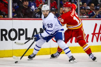 Feb 2, 2026; Calgary, Alberta, CAN; Toronto Maple Leafs left wing Matias MacCelli (63) and Calgary Flames center Morgan Frost (16) battle for the puck during the third period at Scotiabank Saddledome. Mandatory Credit: Sergei Belski-Imagn Images