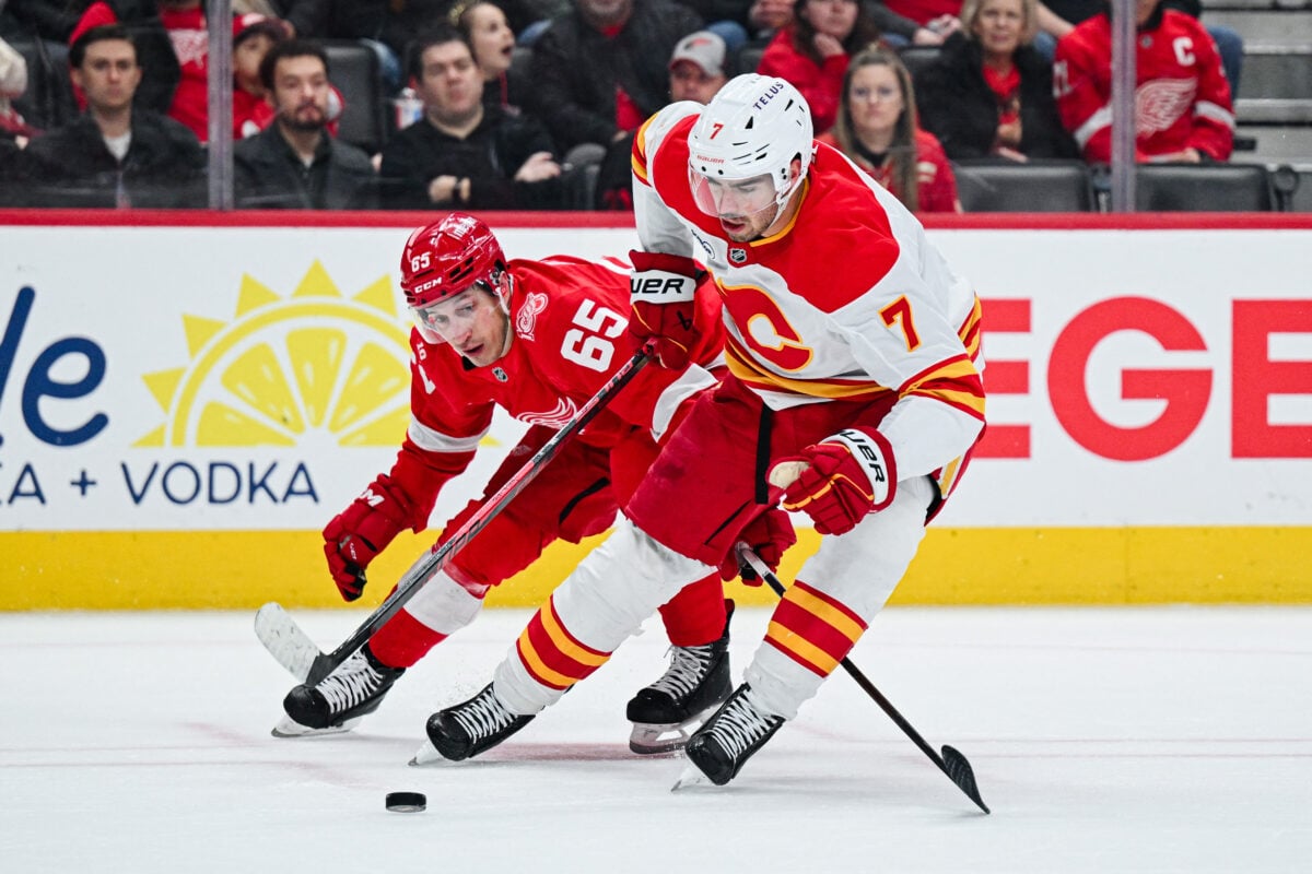 Mar 16, 2026; Detroit, Michigan, USA; Calgary Flames defenseman Kevin Bahl (7) and Detroit Red Wings right wing Dominik Shine (65) battle for the puck during the second period at Little Caesars Arena. Mandatory Credit: Tim Fuller-Imagn Images