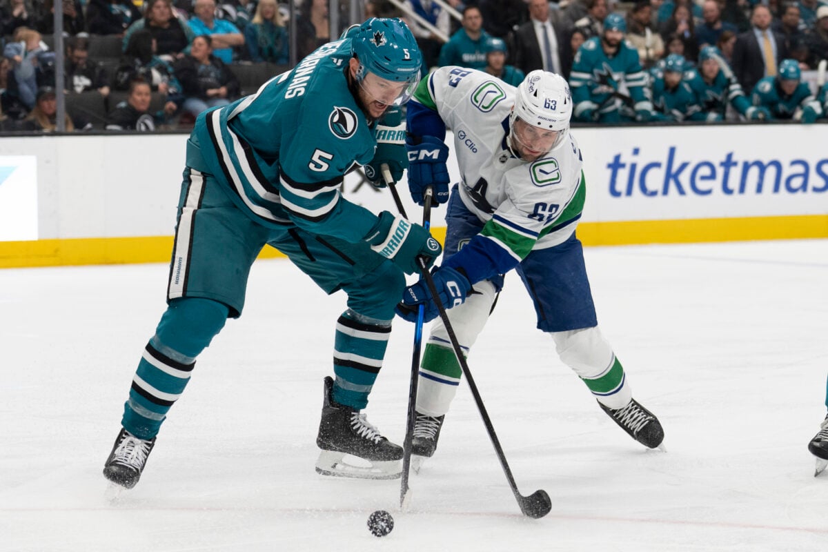 Apr 11, 2026; San Jose, California, USA;  San Jose Sharks defenseman Vincent Desharnais (5) and Vancouver Canucks center Max Sasson (63) battle for control of the puck during the third period at SAP Center at San Jose. Mandatory Credit: Stan Szeto-Imagn Images