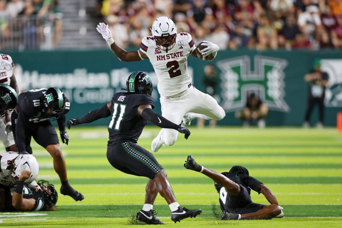 Sep 12, 2026; Honolulu, Hawaii, USA;  New Mexico State Aggies running back James Jones (2) leaps over Hawaii Rainbow Warriors defensive back Jeremiah Hughes (0) during the second quarter at the Clarence T.C. Ching Athletics Complex.  Mandatory Credit: Marco Garcia-Imagn Images
