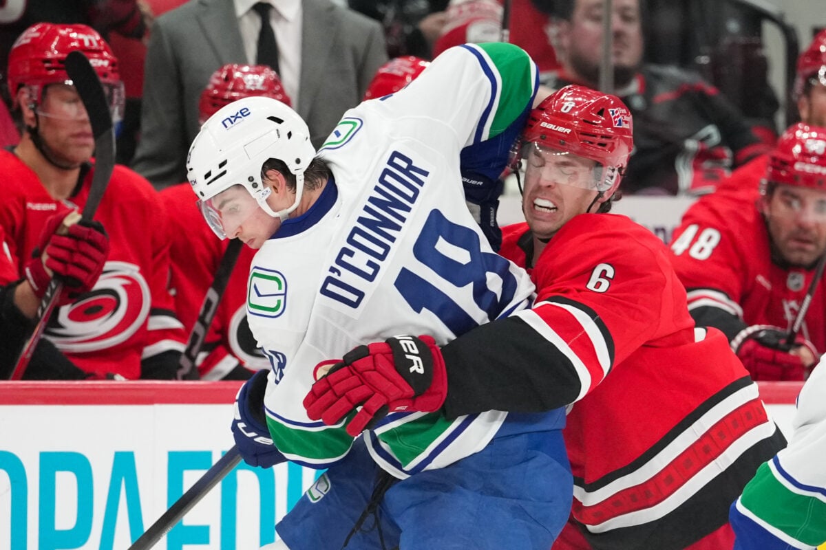 Oct 8, 2026; Raleigh, North Carolina, USA;  Carolina Hurricanes defenseman Mike Reilly (6) checks Vancouver Canucks left wing Drew O'Connor (18) during the third period at Lenovo Center.  Mandatory Credit: James Guillory-Imagn Images