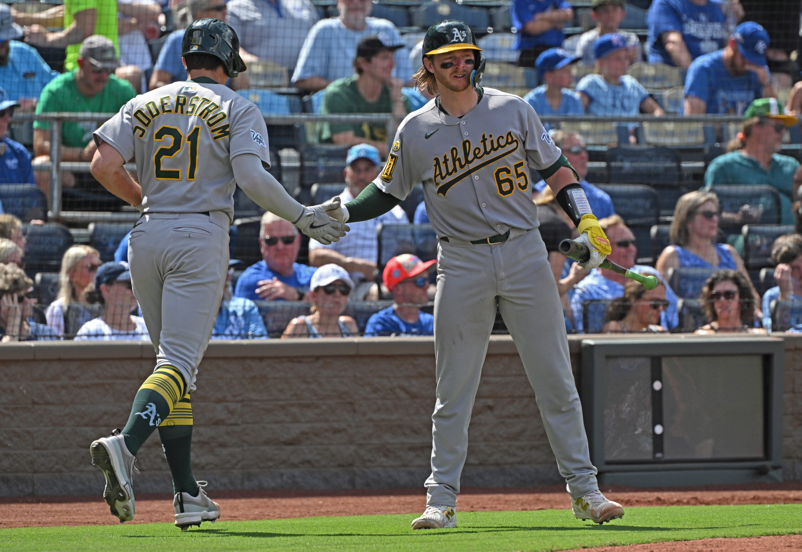 Jun 14, 2025; Kansas City, Missouri, USA;  Athletics left fielder Tyler Soderstrom (21) gets a hand from catcher Willie Maclver (65) after scoring a run in the fourth inning against the Kansas City Royals at Kauffman Stadium. Mandatory Credit: Peter Aiken-Imagn Images