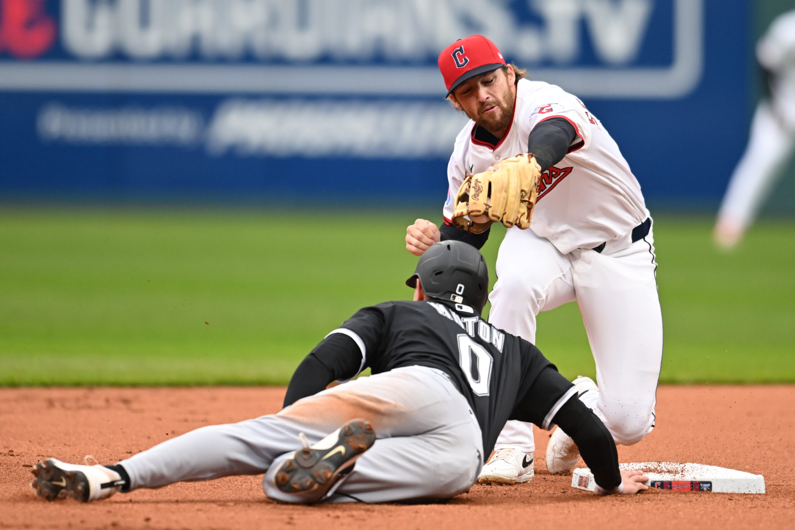 Apr 10, 2025; Cleveland, Ohio, USA; Chicago White Sox designated hitter Nick Maton (0) dives back to second as Cleveland Guardians second baseman Daniel Schneemann (10) is late with the tag during the first inning at Progressive Field. Mandatory Credit: Ken Blaze-Imagn Images