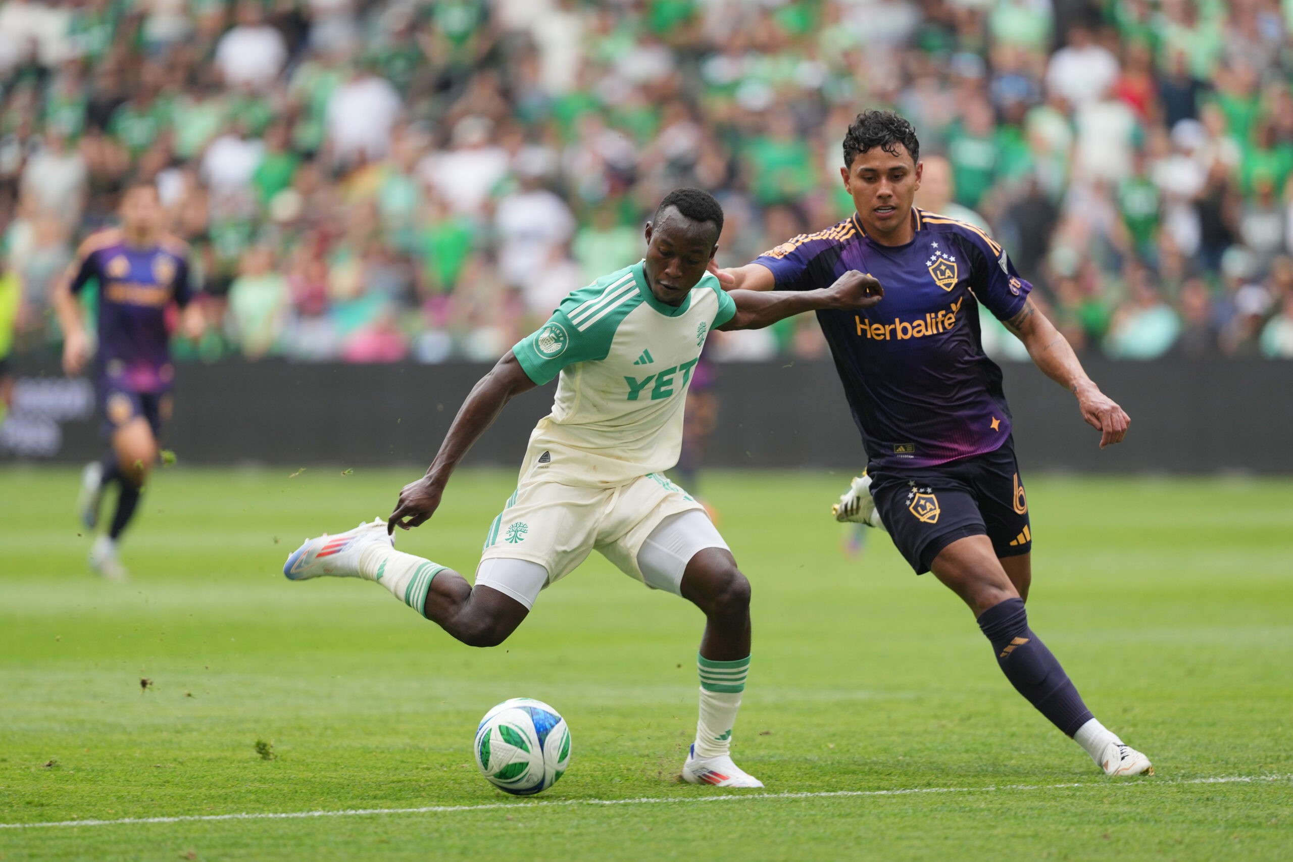 Apr 19, 2025; Austin, Texas, USA; Austin FC forward Osman Bukari (11) dribbles while defended by LA Galaxy  midfielder Edwin Cerrillo (6) during the second half at Q2 Stadium. Mandatory Credit: Scott Wachter-Imagn Images