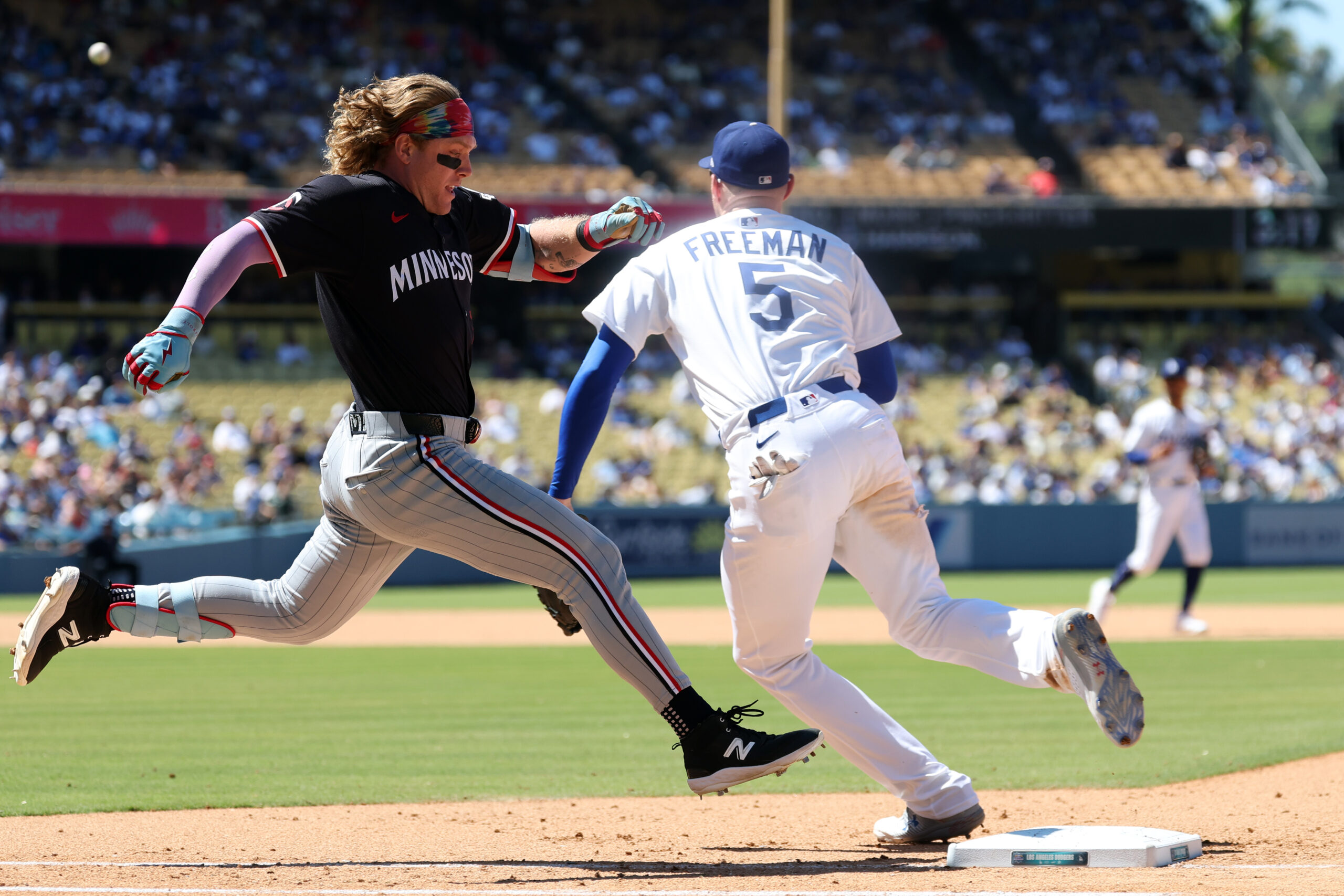 Jul 23, 2025; Los Angeles, California, USA;  Minnesota Twins pinch hitter Harrison Bader (12) beats the throw to Los Angeles Dodgers first baseman Freddie Freeman (5) for an RBI single during the eighth inning at Dodger Stadium. Mandatory Credit: Kiyoshi Mio-Imagn Images