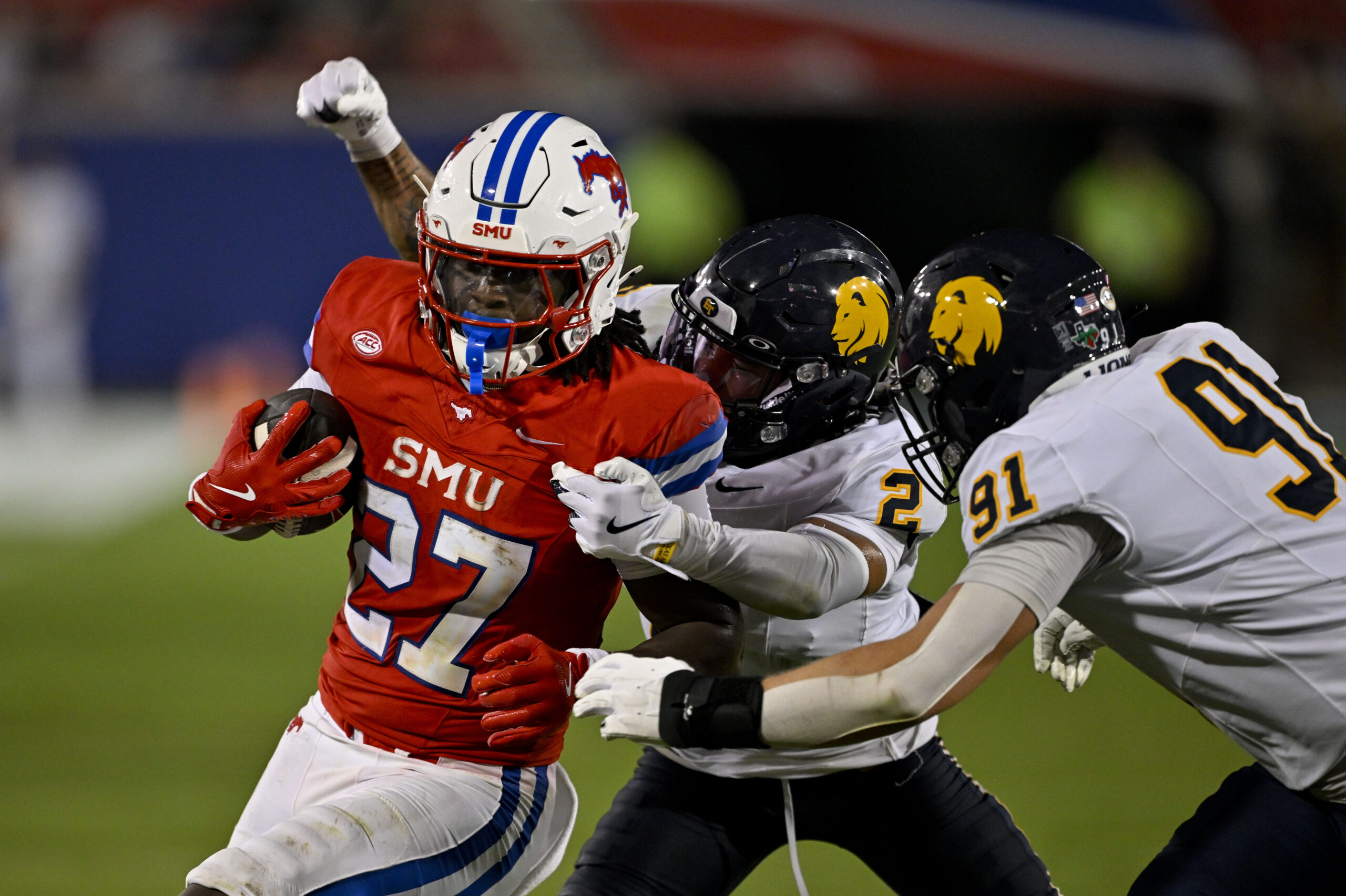 Aug 30, 2025; Dallas, Texas, USA; Southern Methodist Mustangs running back T.J. Harden (27) is tackled by East Texas A&M Lions defensive back Lavon Williams (2) and defensive lineman Micah Johnson (91) during the second half at Gerald J. Ford Stadium. Mandatory Credit: Jerome Miron-Imagn Images
