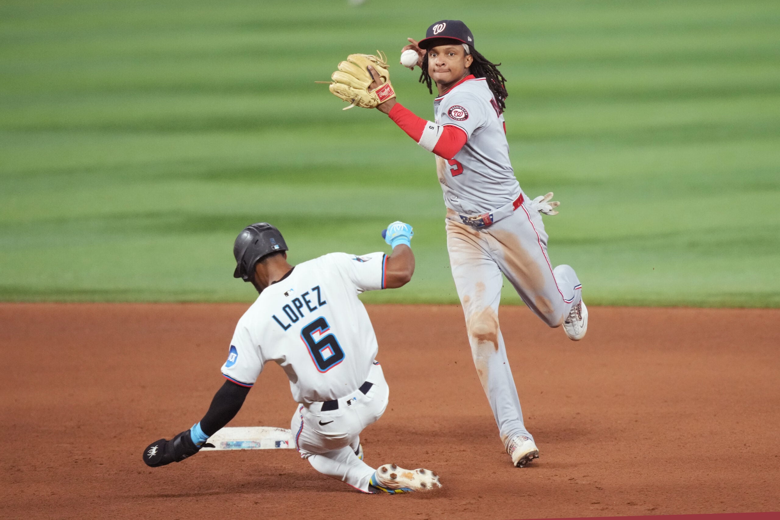 Sep 9, 2025; Miami, Florida, USA;  Washington Nationals shortstop CJ Abrams (5) completes a double play after getting the force out of Miami Marlins shortstop Otto Lopez (6) at second base in the seventh inning at loanDepot Park. Mandatory Credit: Jim Rassol-Imagn Images