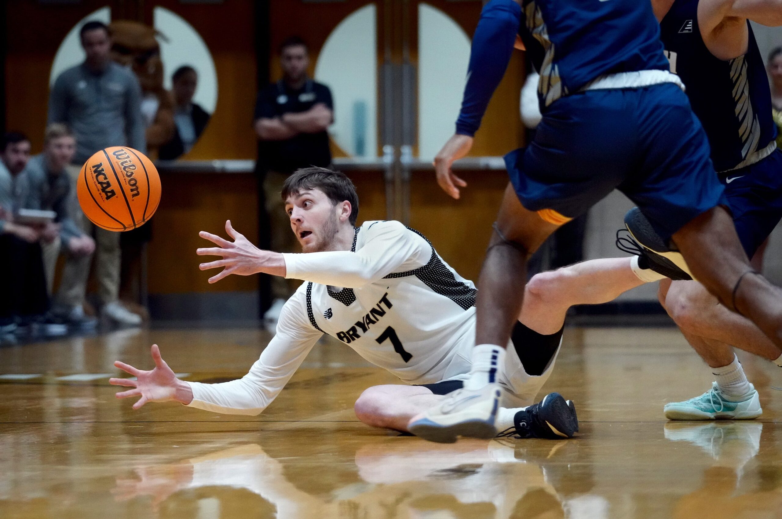 Bryant Bulldogs forward Connor Withers reaches out to recover a loose ball as it bounces away from him after hitting the floor after a trip in the first half. The Bulldogs of Bryant University hosted the University of New Hampshire Wildcats in mens basketball action February 8, 2024.