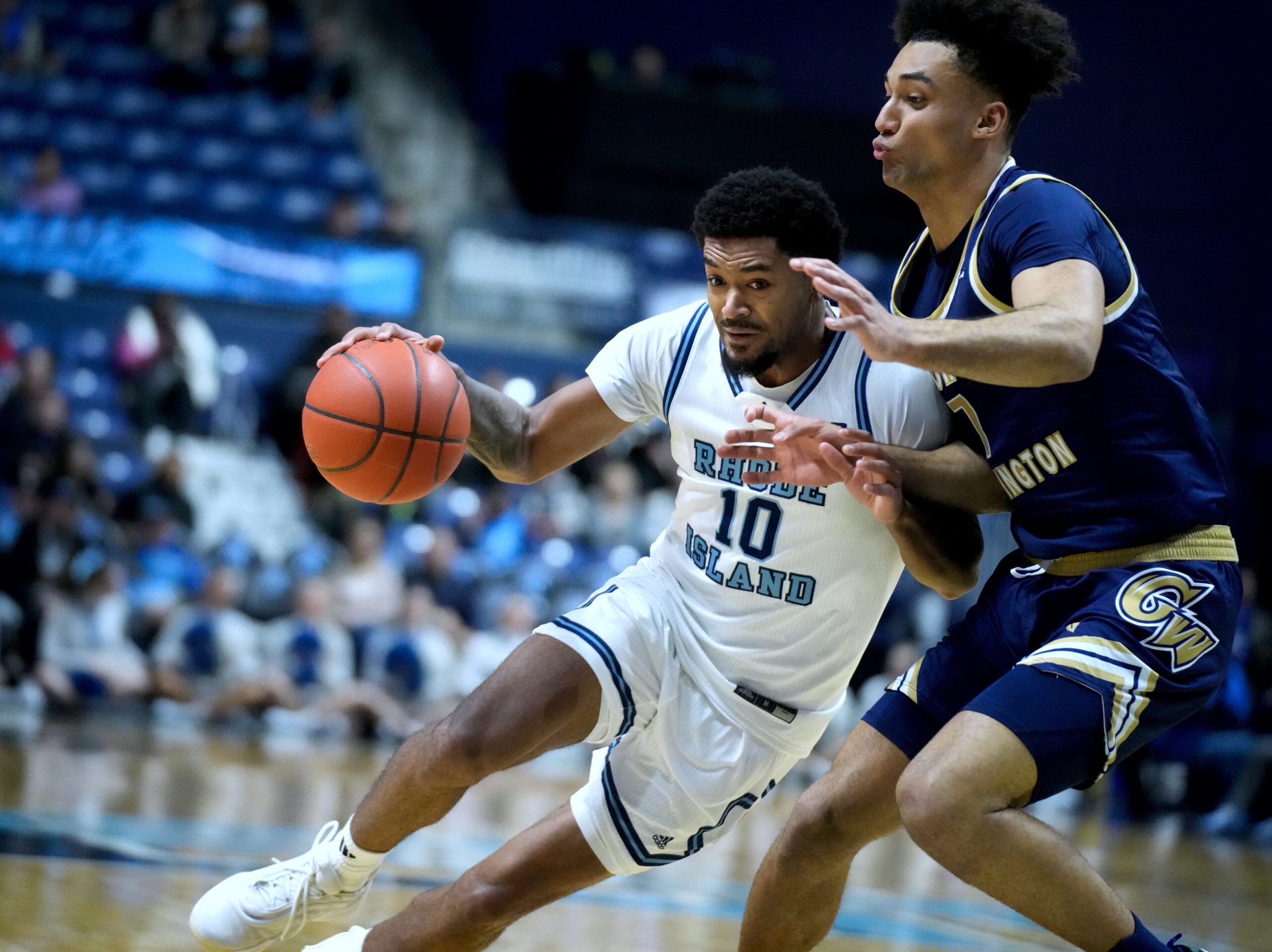 Jamarques Lawrence of URI drives into George Washington defender Dayan Nessah.