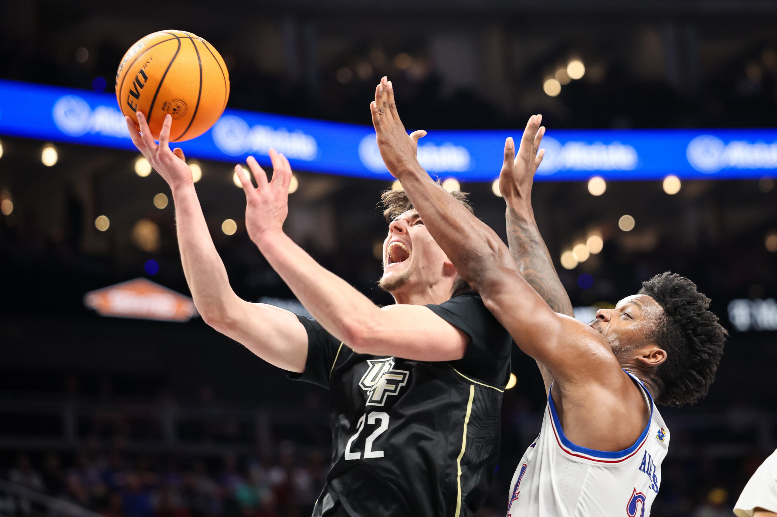 Mar 12, 2025; Kansas City, MO, USA; UCF Knights guard Nils Machowski (22) shoots the ball against Kansas Jayhawks forward KJ Adams Jr. (24) during the second half at T-Mobile Center. Mandatory Credit: William Purnell-Imagn Images