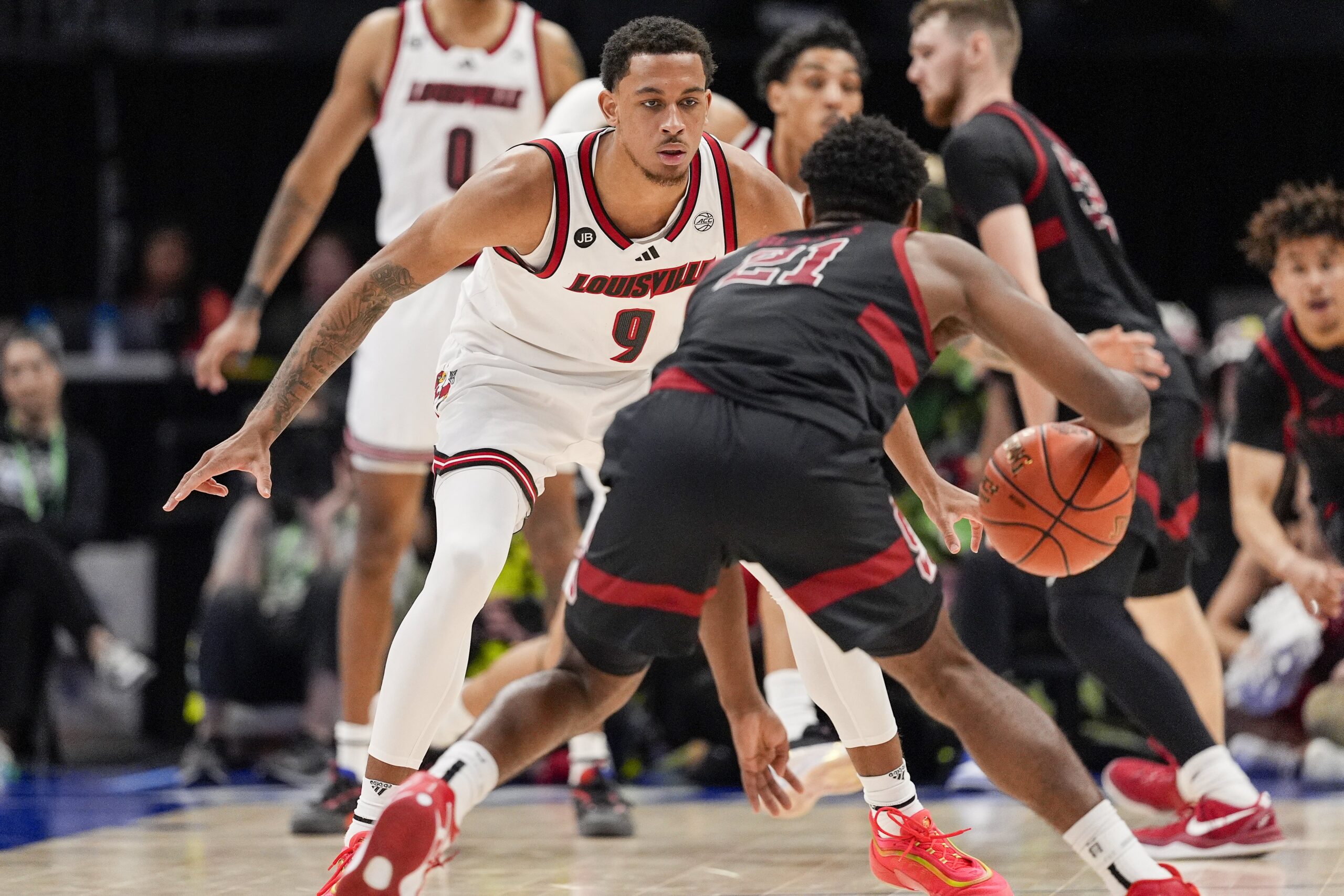 Mar 13, 2025; Charlotte, NC, USA; Louisville Cardinals guard Cole Sherman (4) on defense against Stanford Cardinal guard Jaylen Blakes (21) during the second half at Spectrum Center. Mandatory Credit: Jim Dedmon-Imagn Images