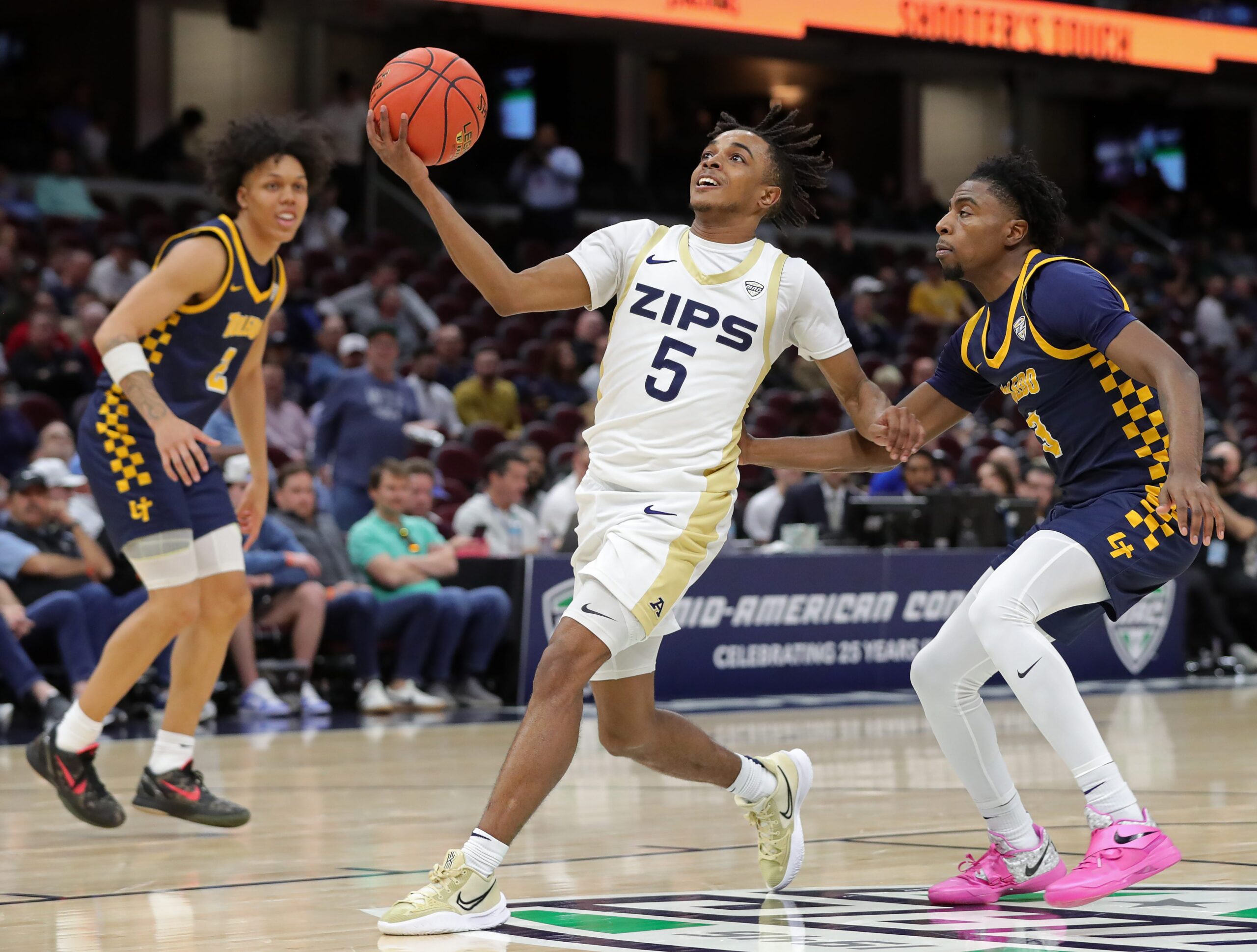 Akron Zips guard Tavari Johnson (5) looks to the basket ahead of Toledo Rockets guard Sonny Wilson (3) during the first half of an NCAA college basketball game in the semifinals of the Mid-American Conference Tournament at Rocket Arena on Friday, March 14, 2025, in Cleveland, Ohio.
