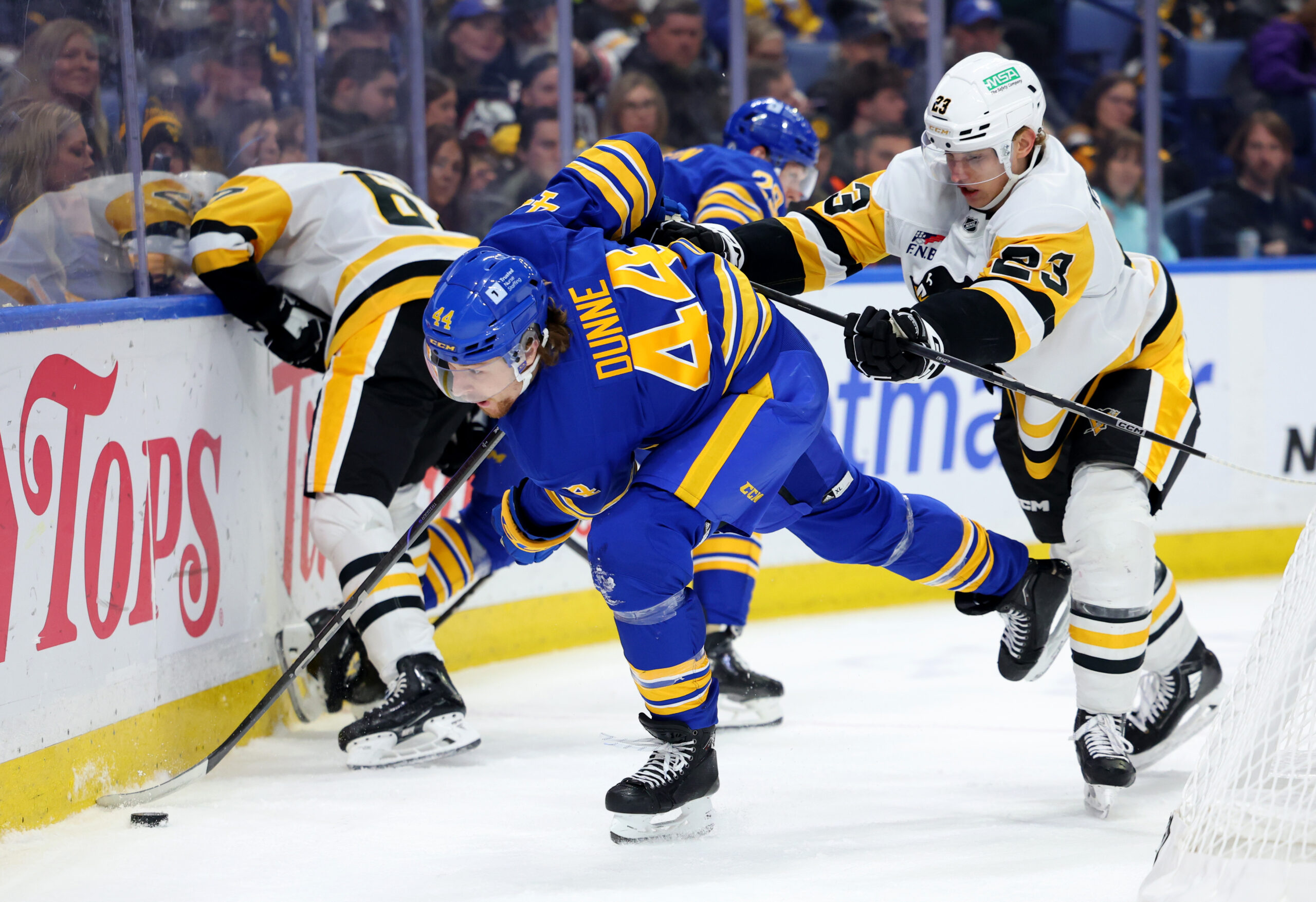 Mar 27, 2025; Buffalo, New York, USA;  Pittsburgh Penguins defenseman Vladislav Kolyachonok (23) checks Buffalo Sabres center Josh Dunne (44) as he plays the puck during the second period at KeyBank Center. Mandatory Credit: Timothy T. Ludwig-Imagn Images