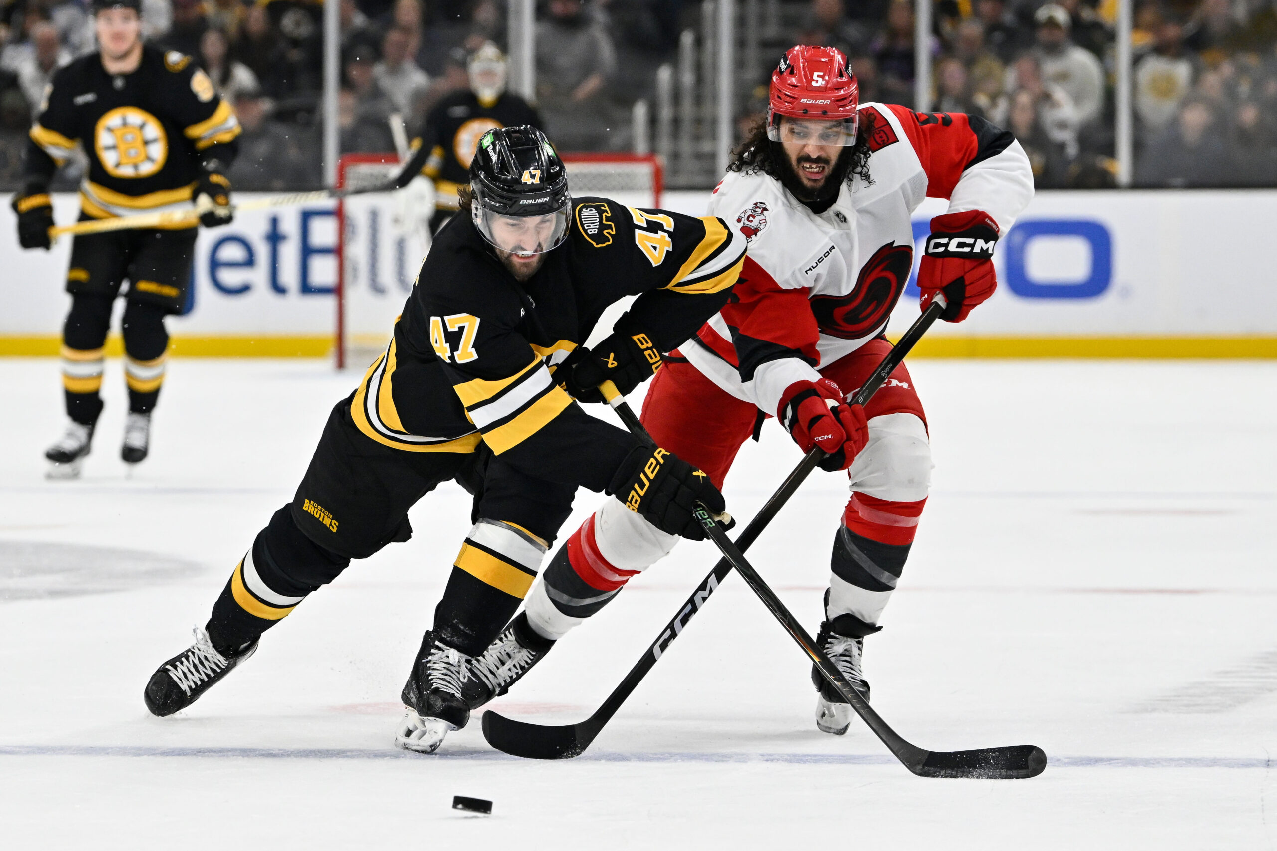Nov 1, 2025; Boston, Massachusetts, USA; Boston Bruins center Mark Kastelic (47) and Carolina Hurricanes defenseman Jalen Chatfield (5) battle for control of the puck  during the third period at TD Garden. Mandatory Credit: Eric Canha-Imagn Images