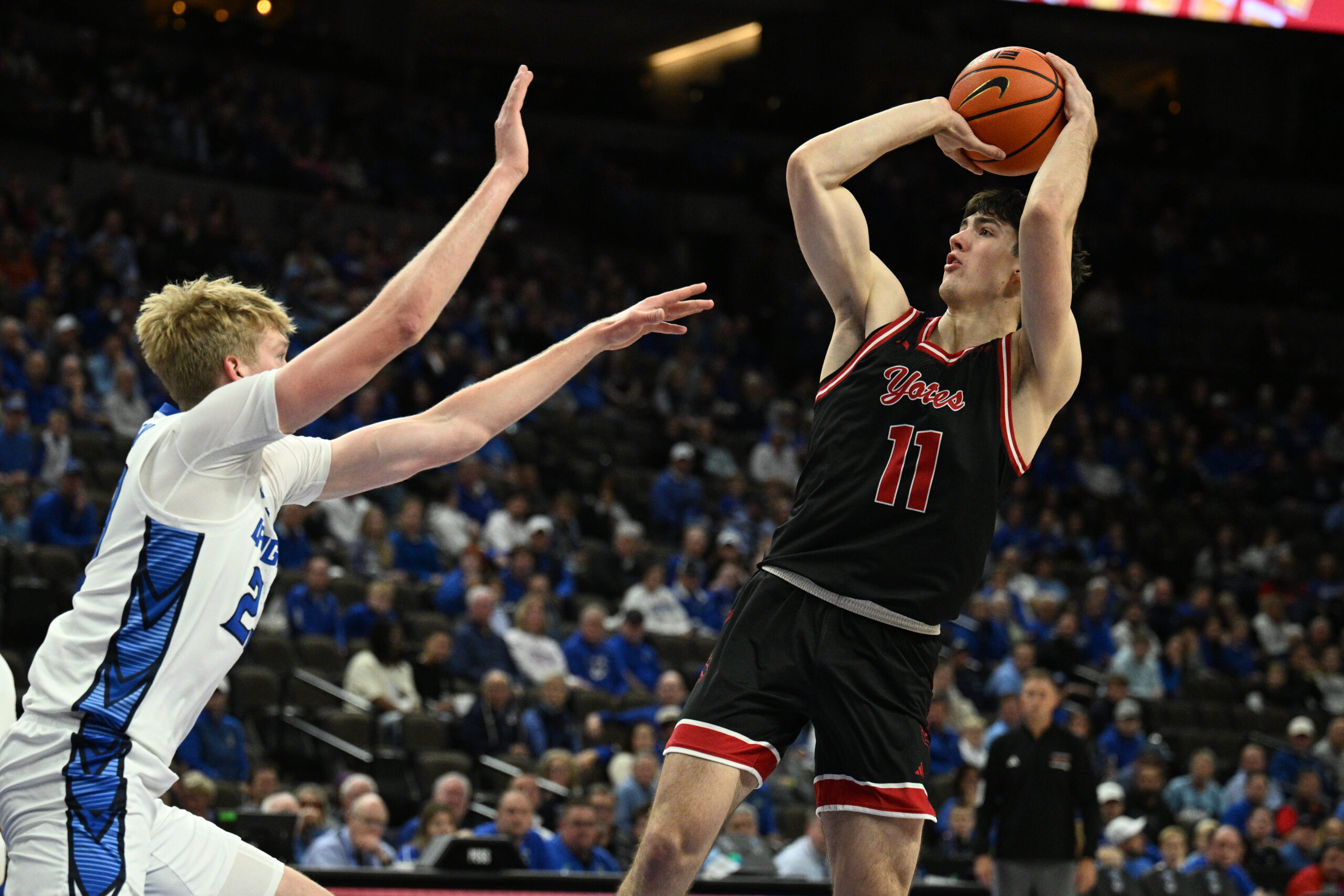 Nov 5, 2025; Omaha, Nebraska, USA; South Dakota Coyotes guard Jesse McIntosh (11) attempts a shot over Creighton Bluejays forward Jackson McAndrew (23) during the first half at CHI Health Center Omaha. Mandatory Credit: Steven Branscombe-Imagn Images