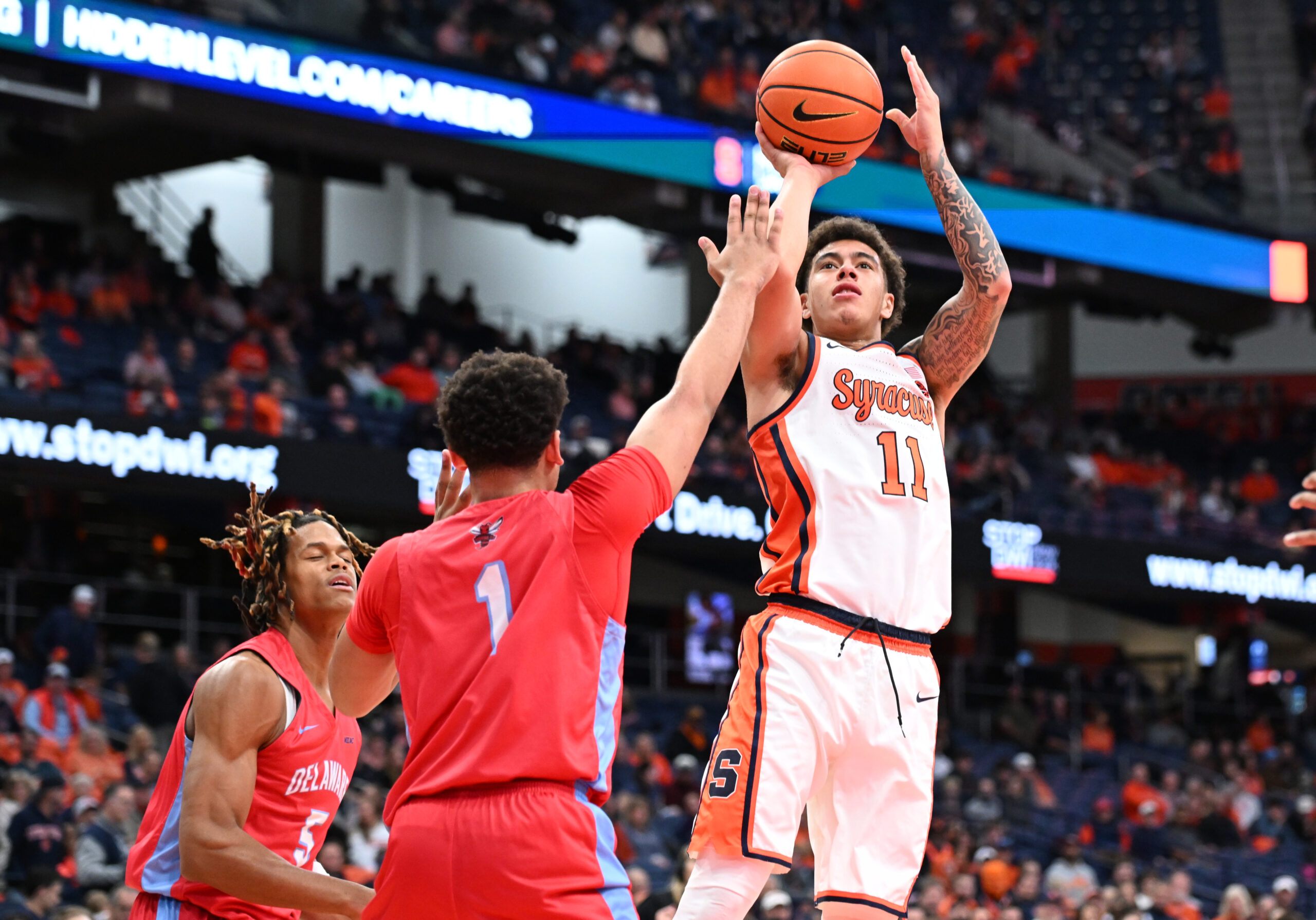 Nov 8, 2025; Syracuse, New York, USA; Syracuse Orange guard Naithan George (11) shoots the ball over Delaware State Hornets guard Ponce James (1) and guard John Clemmons (5) in the second half at the JMA Wireless Dome. Mandatory Credit: Mark Konezny-Imagn Images