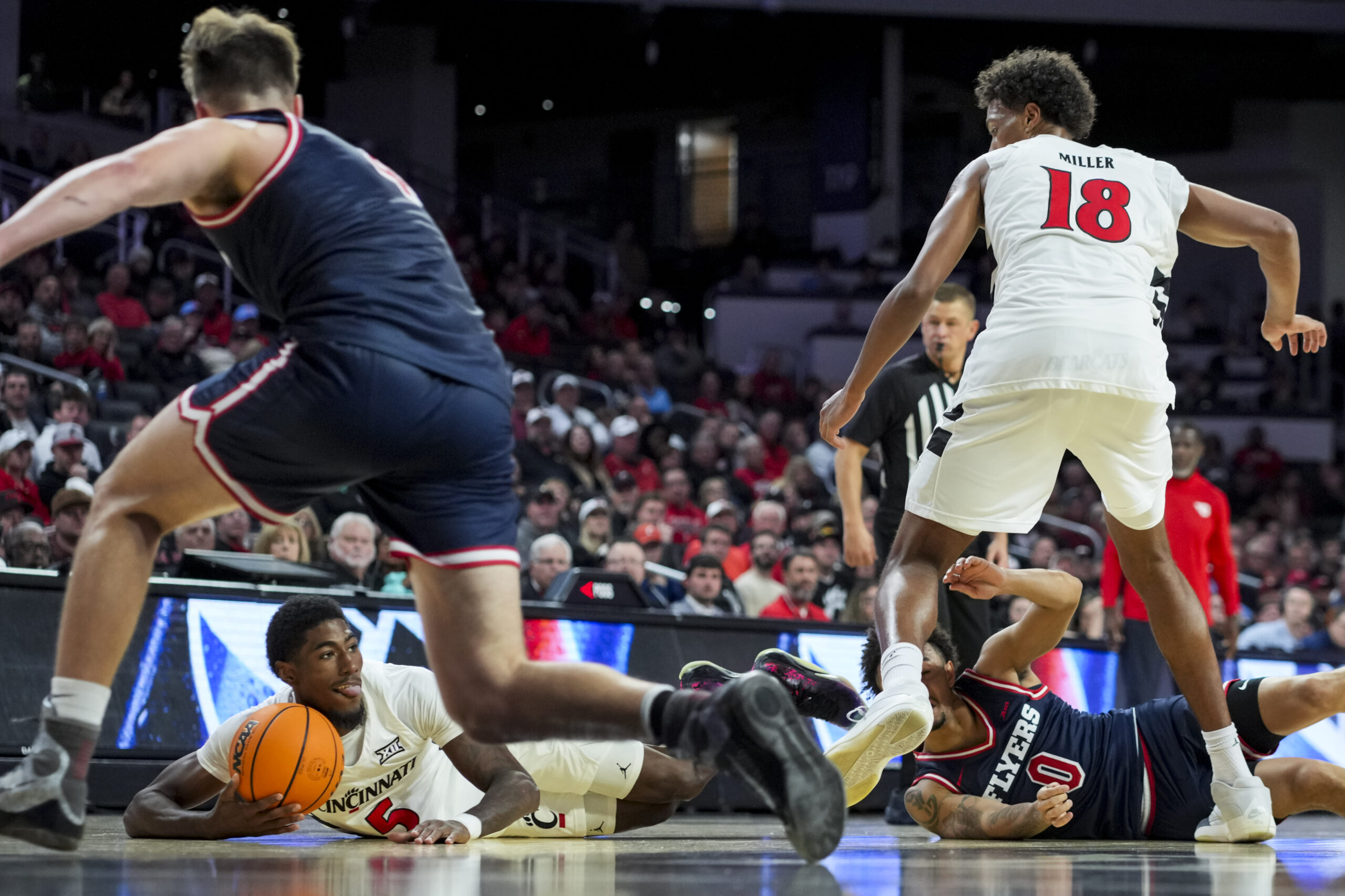 Nov 11, 2025; Cincinnati, Ohio, USA; Cincinnati Bearcats guard Sencire Harris (5) jumps on the loose ball against Dayton Flyers guard Javon Bennett (0) in the second half at Fifth Third Arena. Mandatory Credit: Aaron Doster-Imagn Images