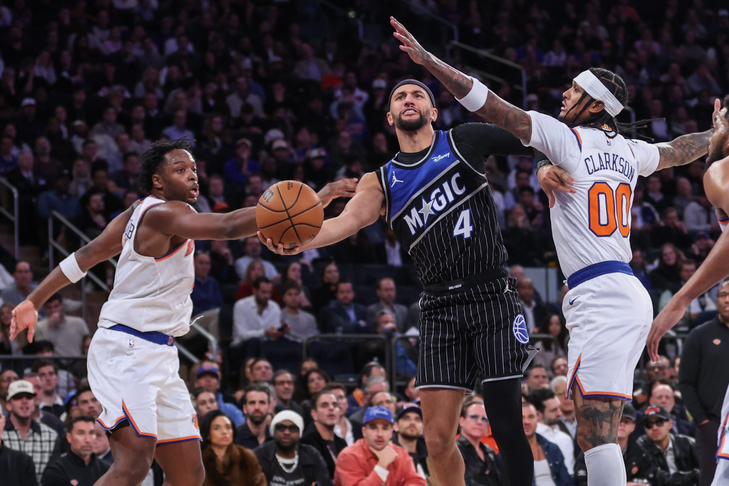 Nov 12, 2025; New York, New York, USA;  Orlando Magic guard Jalen Suggs (4) drives past New York Knicks forward OG Anunoby (8) and guard Jordan Clarkson (00) in the fourth quarter at Madison Square Garden. Mandatory Credit: Wendell Cruz-Imagn Images