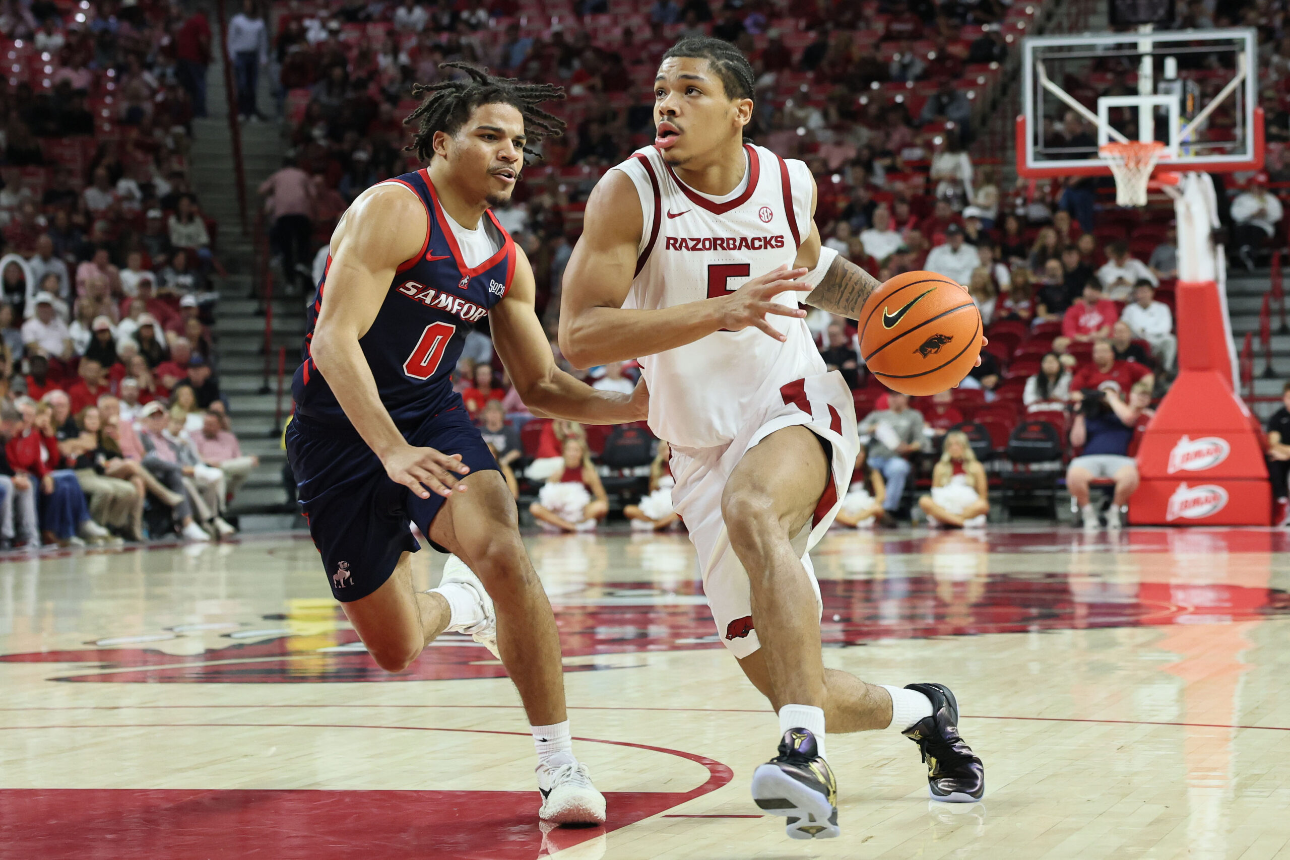 Nov 14, 2025; Fayetteville, Arkansas, USA; Arkansas Razorbacks guard Darius Acuff Jr (5) drives against Samford Bulldogs guard Isaiah Campbell-Finch (0) during the second half at Bud Walton Arena. Arkansas won 79-75. Mandatory Credit: Nelson Chenault-Imagn Images