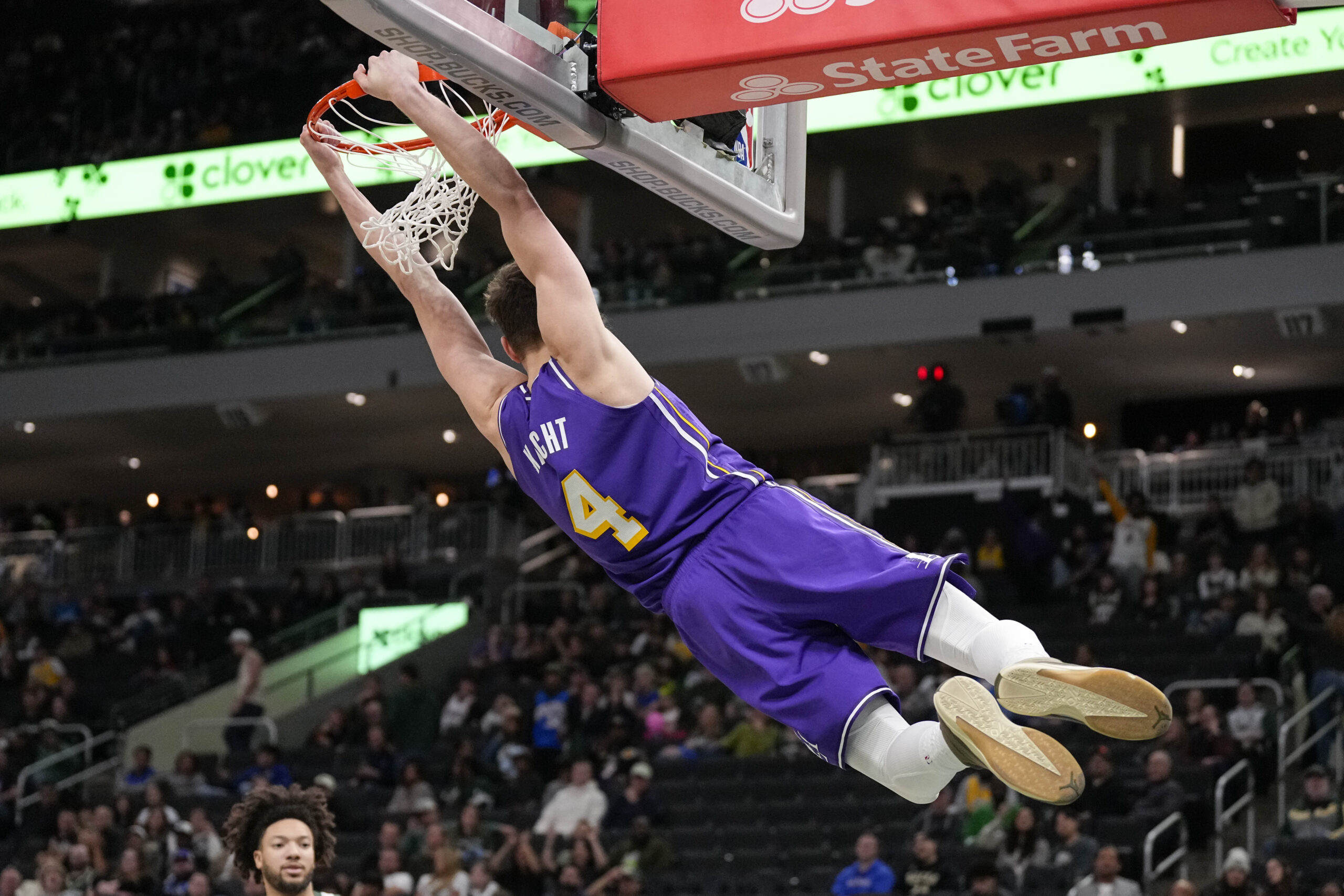Nov 15, 2025; Milwaukee, Wisconsin, USA;  Los Angeles Lakers guard Dalton Knecht (4) hangs from the rim following a slam dunk during the fourth quarter against the Milwaukee Bucks at Fiserv Forum. Mandatory Credit: Jeff Hanisch-Imagn Images