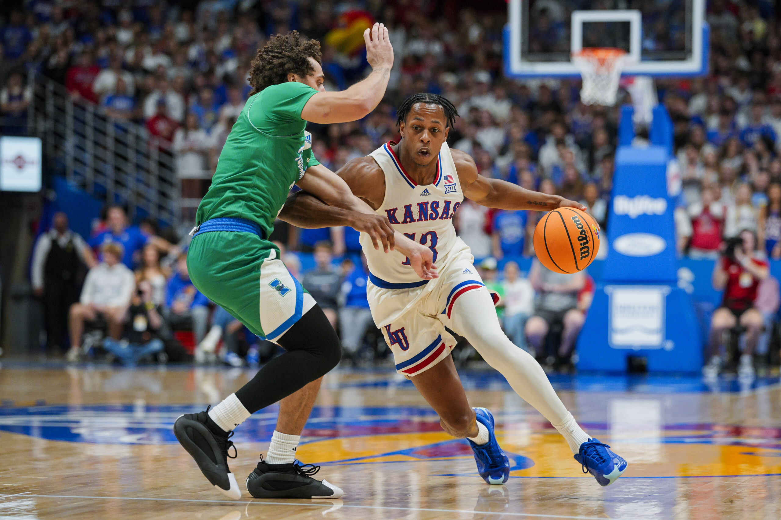 Nov 11, 2025; Lawrence, Kansas, USA; Kansas Jayhawks guard Elmarko Jackson (13) drives against Texas A&M-Corpus Christi Islanders forward Jaden Haire (11) during the first half at Allen Fieldhouse. Mandatory Credit: Jay Biggerstaff-Imagn Images