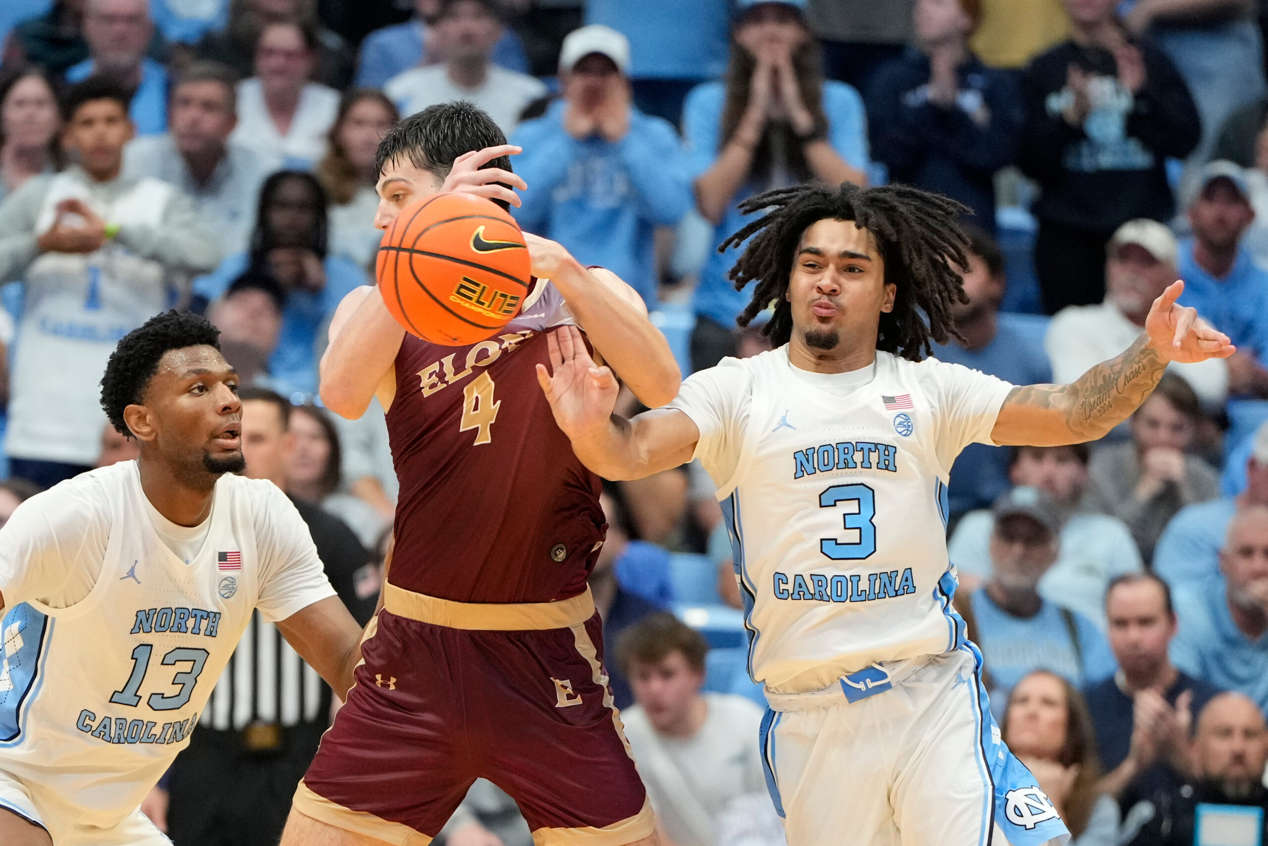 Nov 4, 2024; Chapel Hill, North Carolina, USA;  North Carolina Tar Heels guard Elliot Cadeau (3) strips the ball from Elon Phoenix forward Sam Sherry (4) as forward Jalen Washington (13) helps defend in the second half at Dean E. Smith Center. Mandatory Credit: Bob Donnan-Imagn Images