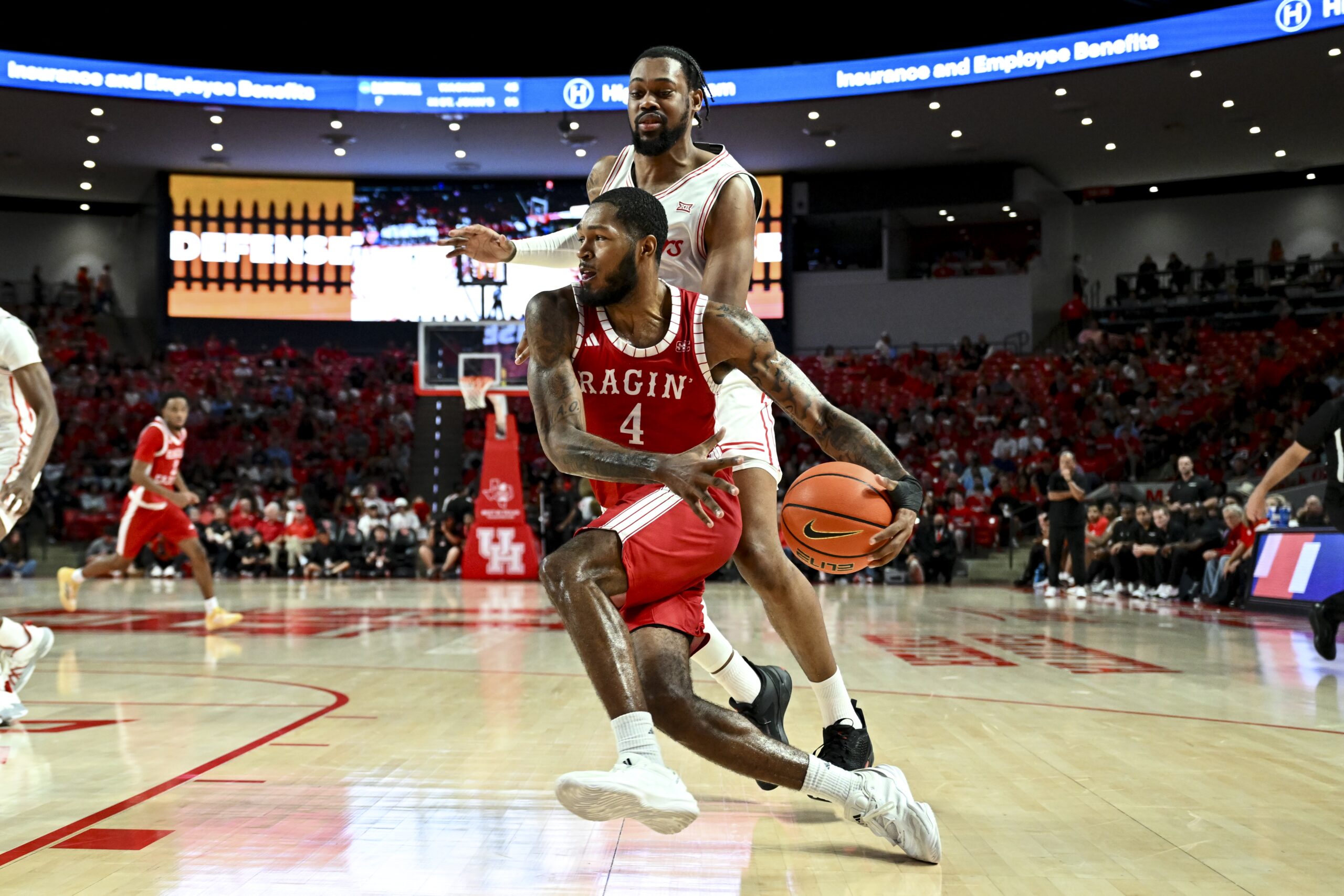 Nov 13, 2024; Houston, Texas, USA; Louisiana Ragin Cajuns guard Kyndall Davis (4) drives past Houston Cougars forward J'Wan Roberts (13) during the second half at Fertitta Center. The Cougars defeated the Ragin Cajuns 91-45. Mandatory Credit: Maria Lysaker-Imagn Images