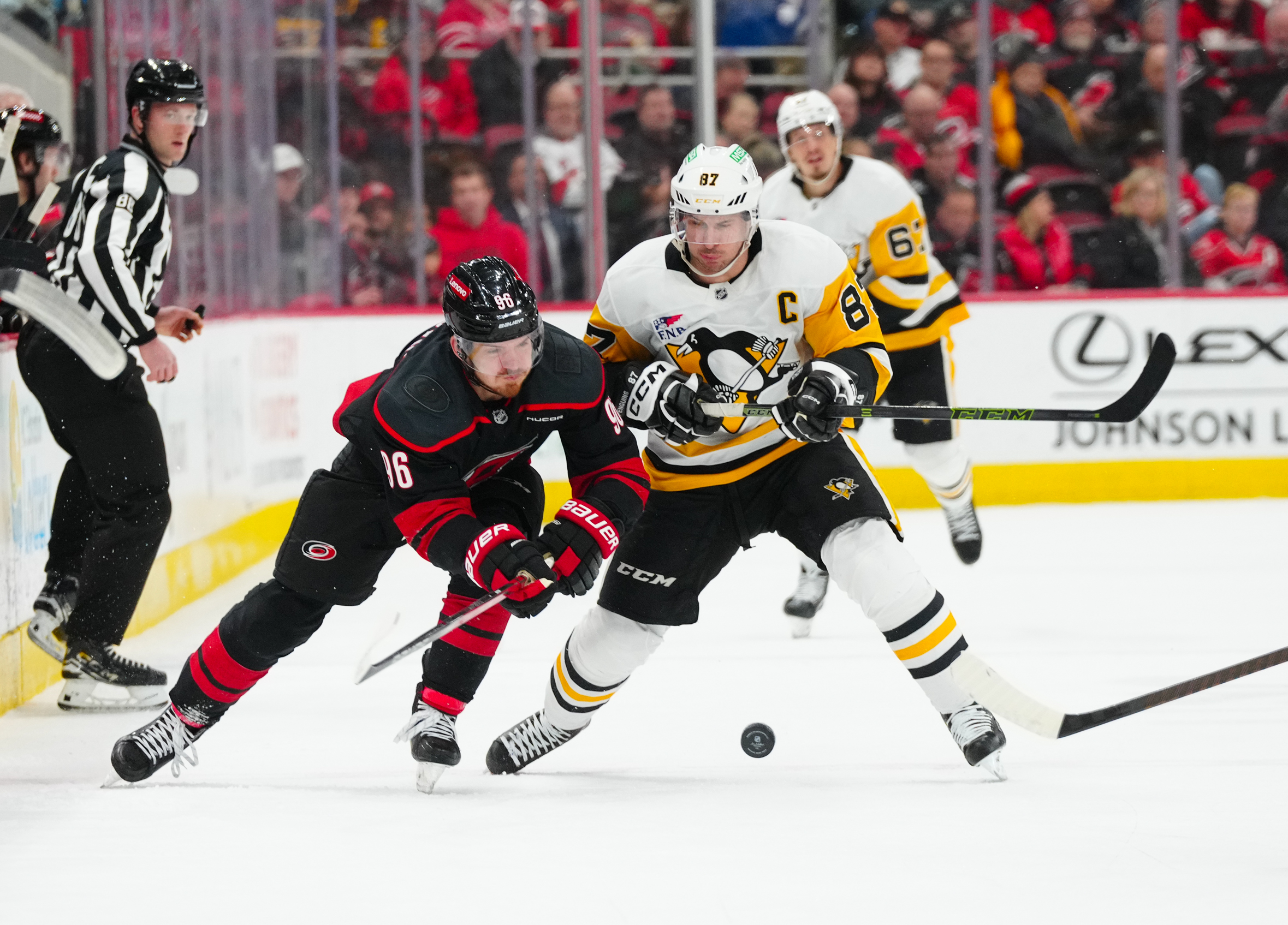 Jan 5, 2025; Raleigh, North Carolina, USA;  Carolina Hurricanes center Jack Roslovic (96) and Pittsburgh Penguins center Sidney Crosby (87) battle over the puck during the third period at Lenovo Center. Mandatory Credit: James Guillory-Imagn Images