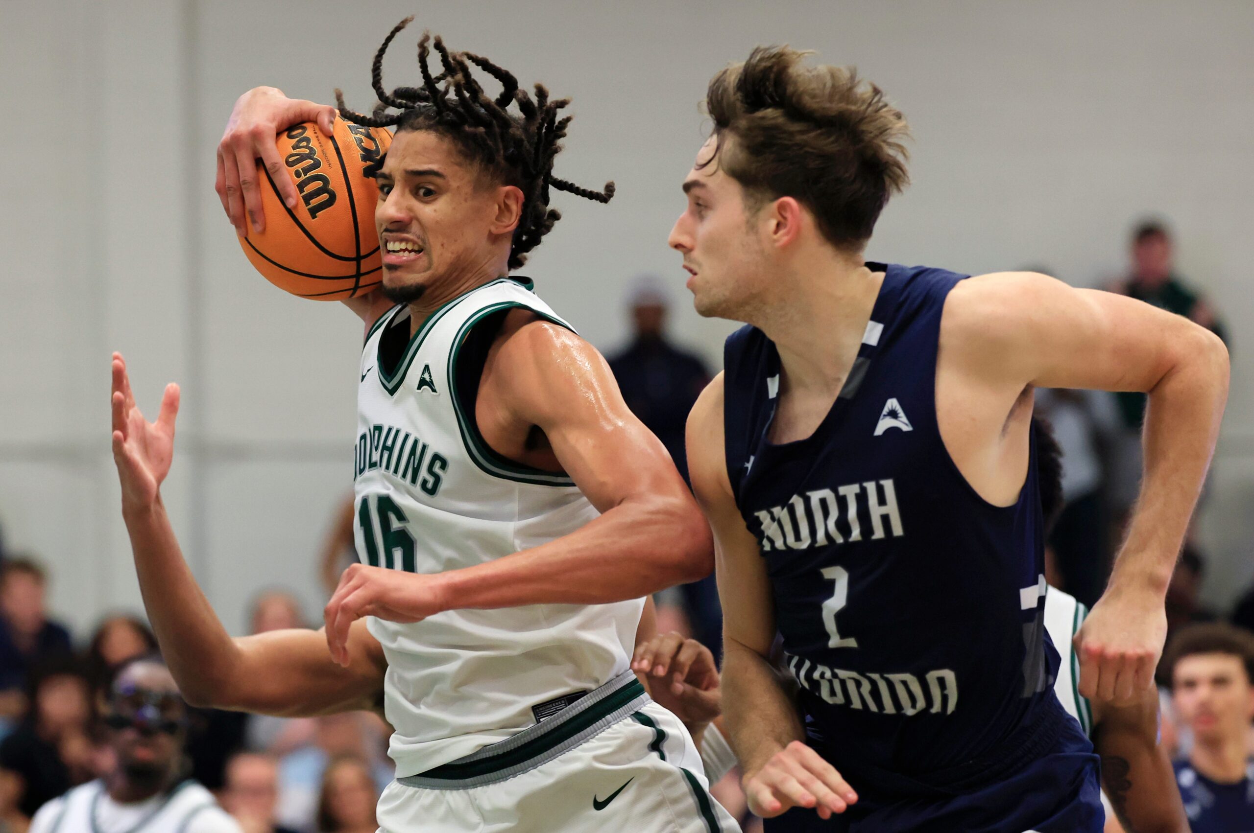 Jacksonville Dolphins forward Zimi Nwokeji (16) grabs a rebound as North Florida Ospreys guard Nate Lliteras (2) looks on during the second half of an NCAA men’s basketball matchup Saturday, Feb. 1, 2025 at Jacksonville University in Jacksonville, Fla. UNF held off a late rally from JU defeating them 81-78. [Corey Perrine/Florida Times-Union]