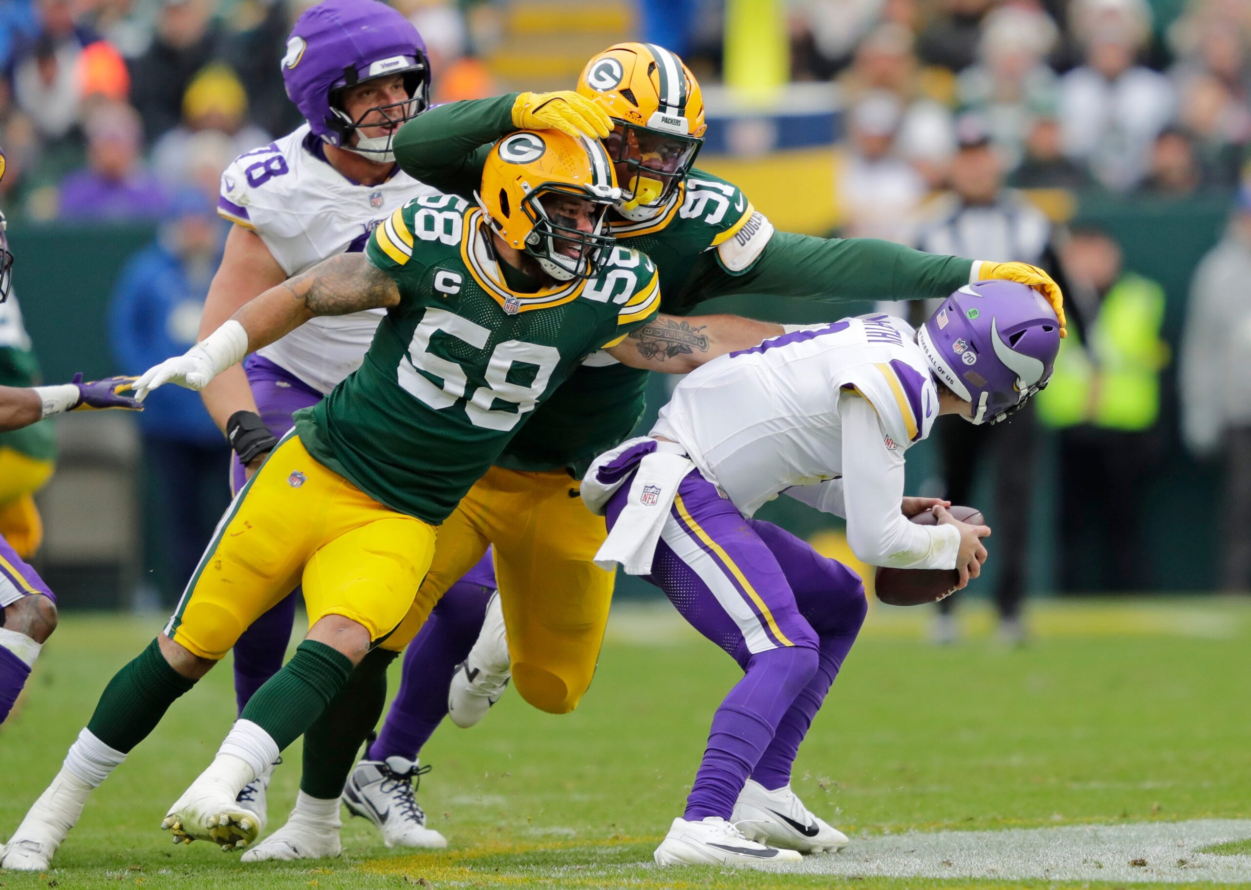 Nov 23, 2025; Green Bay, Wisconsin, USA; Green Bay Packers' Isaiah McDuffie (58) and Warren Brinson (91) sack Minnesota Vikings quarterback J.J. McCarthy (9) in the second quarter during their football game at Lambeau Field. Mandatory Credit: Dan Powers-USA TODAY Network via Imagn Images