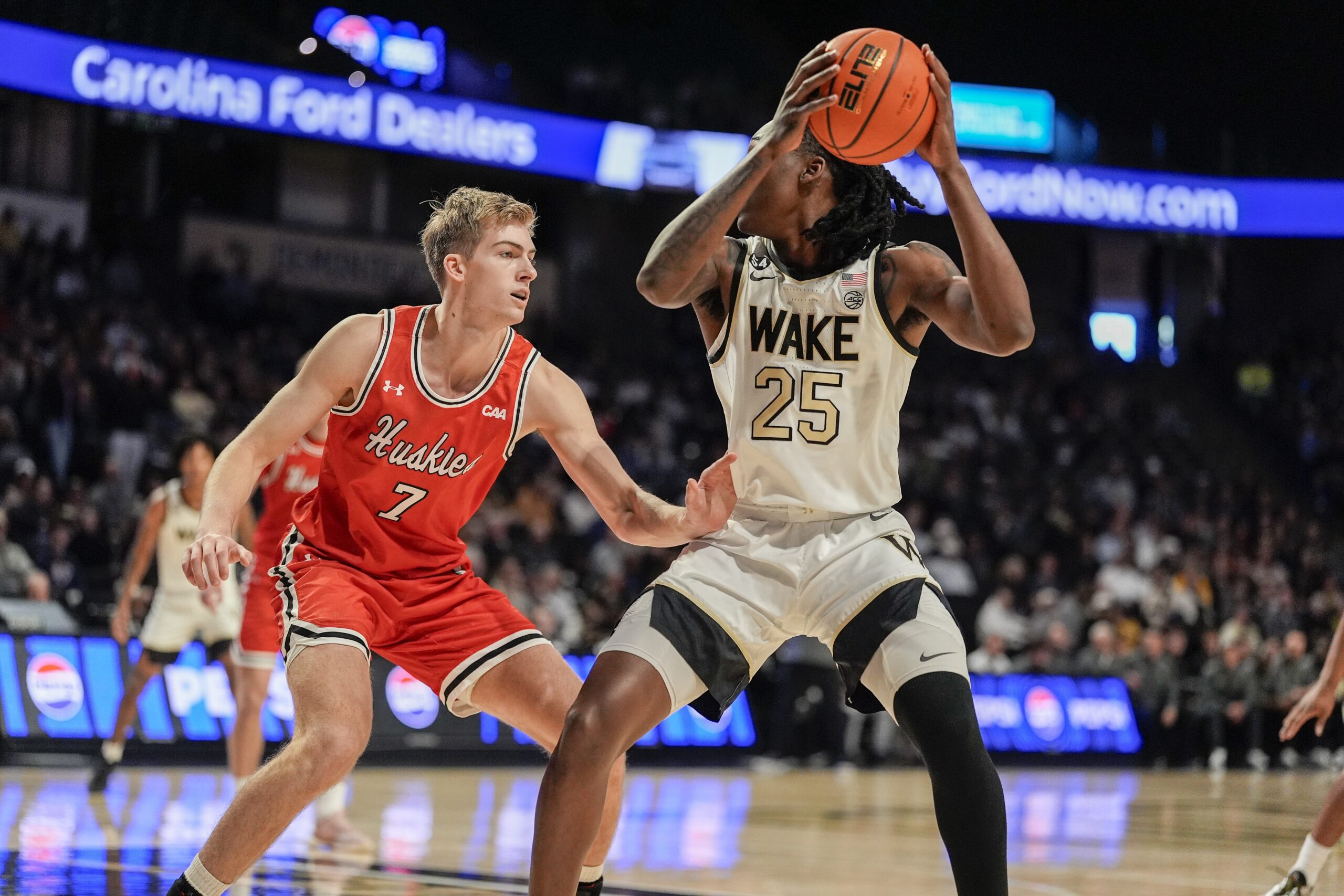 Nov 28, 2025; Winston-Salem, North Carolina, USA;  Wake Forest Demon Deacons forward Tre'Von Spillers (25) handles the ball against Northeastern Huskies forward Youri Fritz (7) during the first half at Lawrence Joel Veterans Memorial Coliseum. Mandatory Credit: Jim Dedmon-Imagn Images