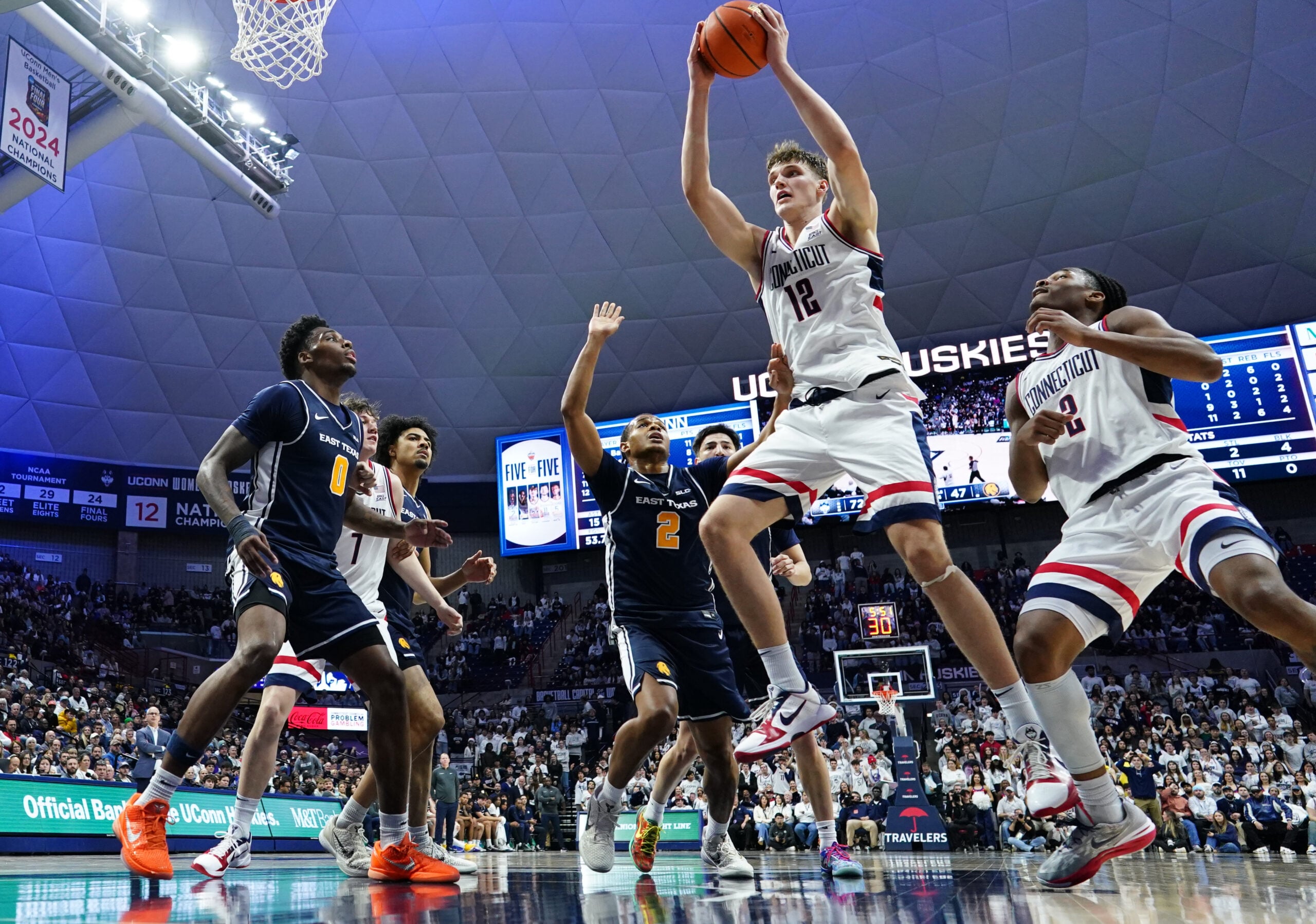 Dec 5, 2025; Storrs, Connecticut, USA; UConn Huskies center Eric Reibe (12) grabs the rebound  against the East Texas A&M Lions in the second half at Harry A. Gampel Pavilion. Mandatory Credit: David Butler II-Imagn Images