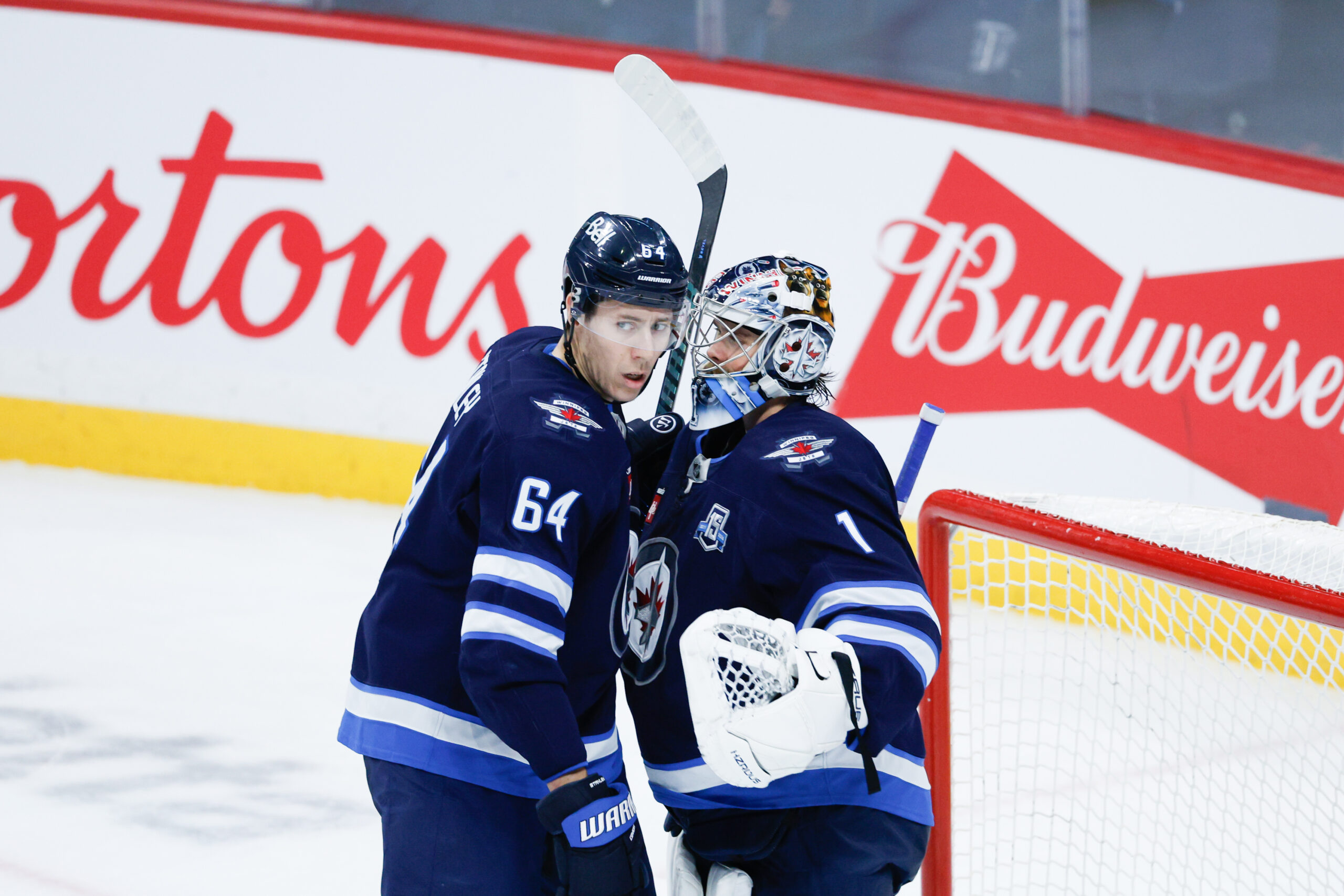 Dec 5, 2025; Winnipeg, Manitoba, CAN;  Winnipeg Jets goalie Eric Comrie (1) is congratulated by defenseman Logan Stanley (64) on his win against the Buffalo Sabres during the third period at Canada Life Centre. Mandatory Credit: Terrence Lee-Imagn Images