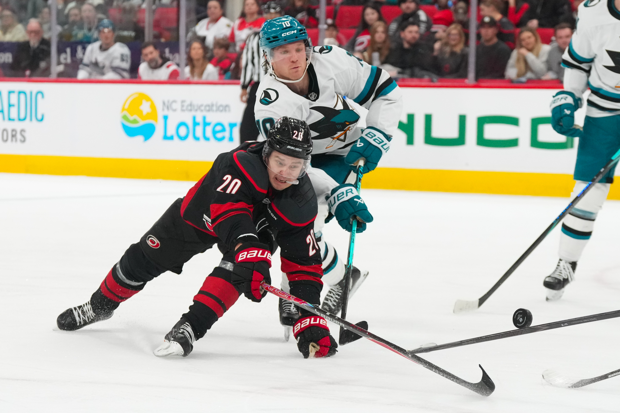 Dec 7, 2025; Raleigh, North Carolina, USA;  Carolina Hurricanes center Sebastian Aho (20) and San Jose Sharks center Ty Dellandrea (10) battle over the puck during the third period at Lenovo Center. Mandatory Credit: James Guillory-Imagn Images
