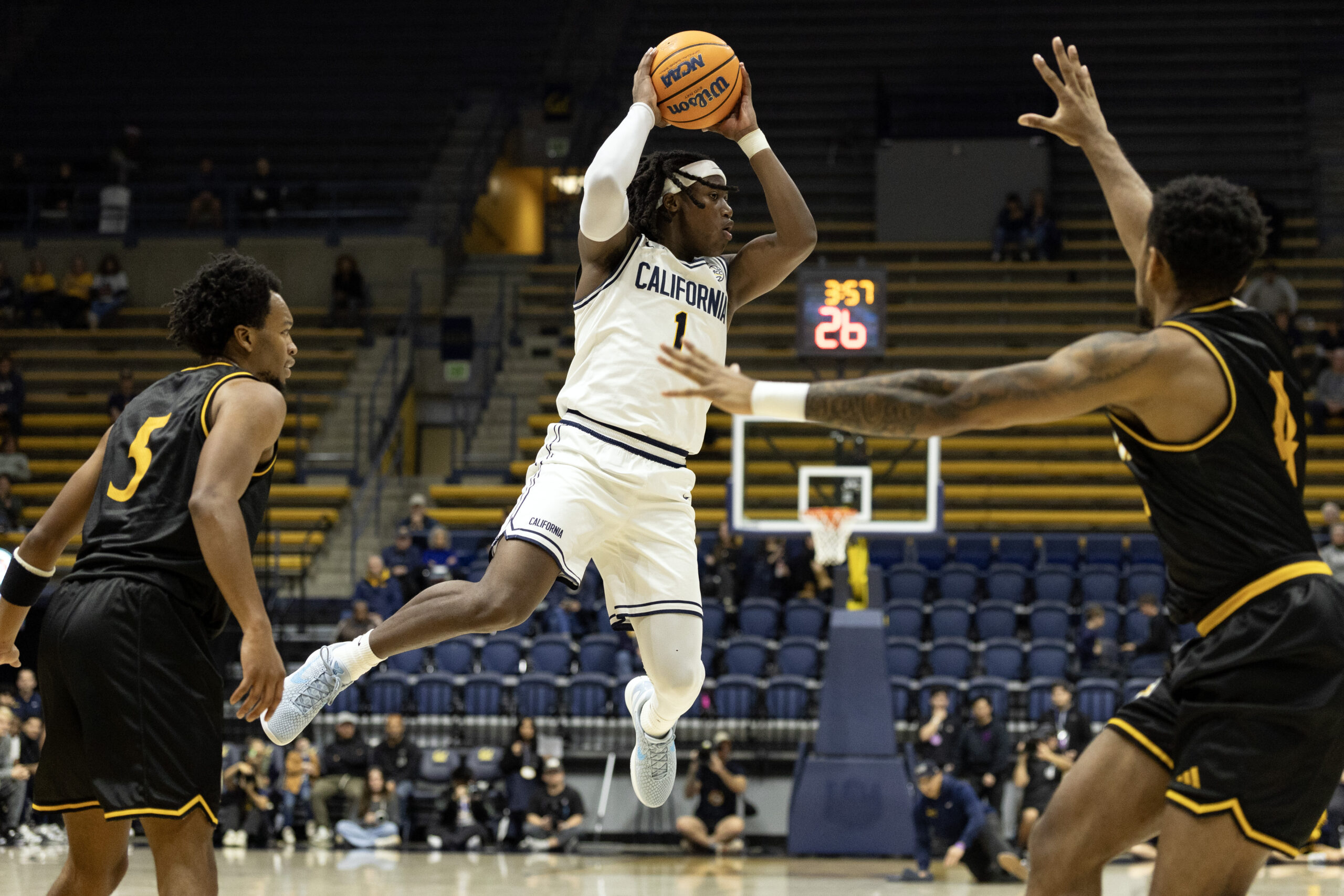 Dec 9, 2025; Berkeley, California, USA; California Golden Bears guard DeJuan (DJ) Campbell (1) leaves his feet to pass between Dominican Penguins defender Darius Best (5) and Omari Davis (4) during the first half at Haas Pavilion. Mandatory Credit: D. Ross Cameron-Imagn Images