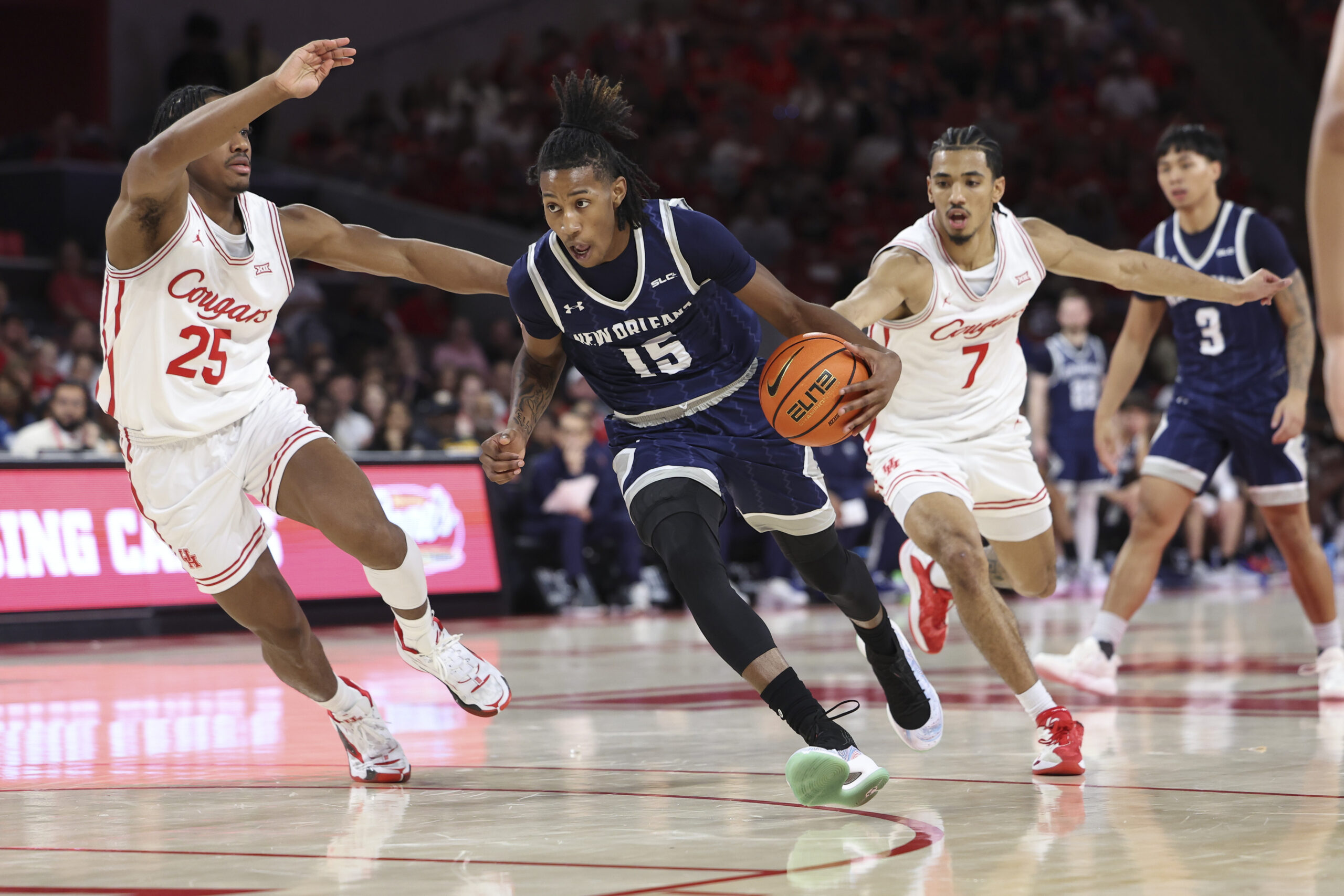 Dec 13, 2025; Houston, Texas, USA; New Orleans Privateers guard Jamal Chretien II (15) drives with the ball as Houston Cougars guard Milos Uzan (7) defends during the first half at Fertitta Center. Mandatory Credit: Troy Taormina-Imagn Images