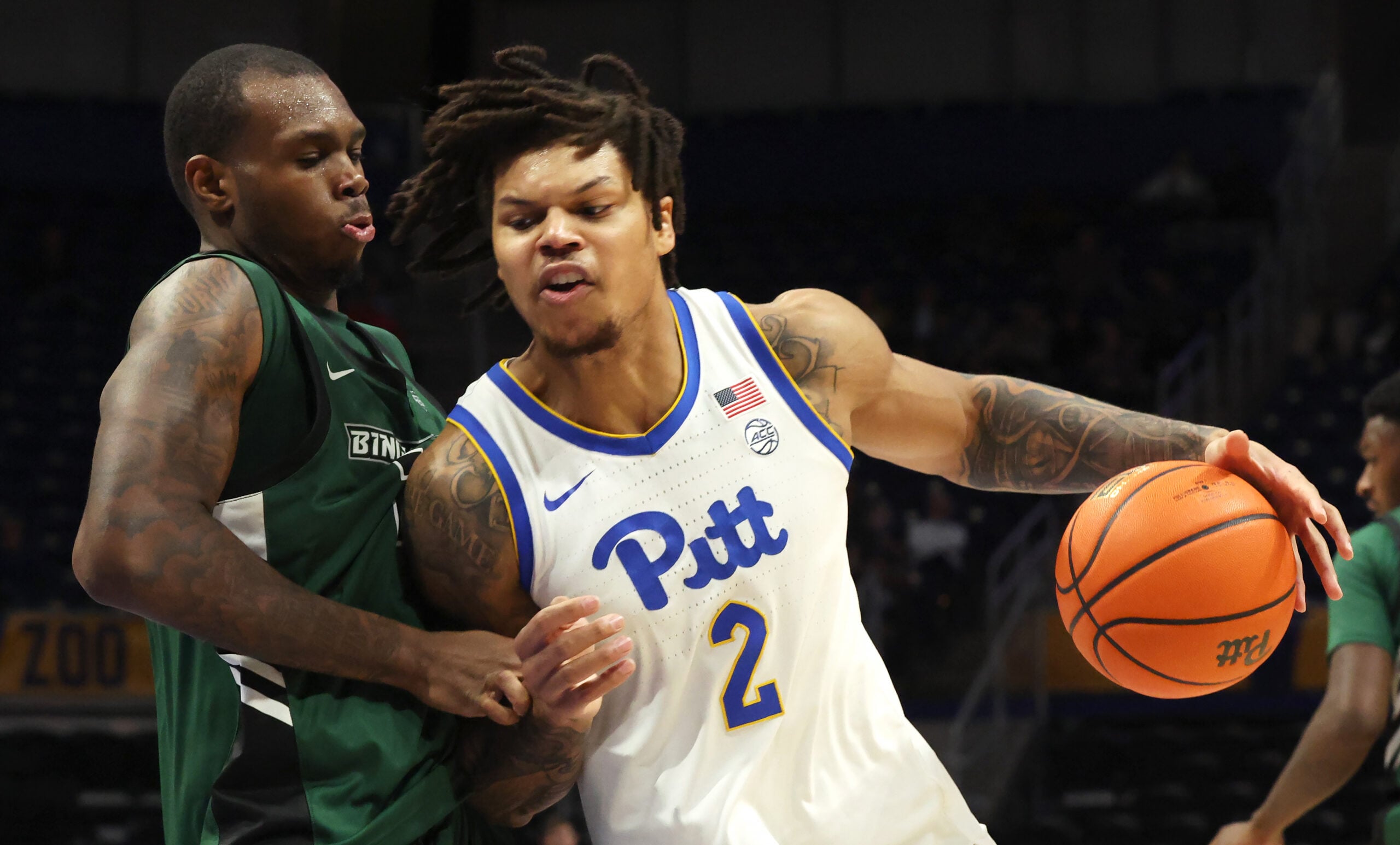 Dec 17, 2025; Pittsburgh, Pennsylvania, USA;  Pittsburgh Panthers forward Cameron Corhen (2) dribbles the ball against pressure from Binghamton Bearcats center Demetrius Lilley (left) during the second half at the Petersen Events Center. Mandatory Credit: Charles LeClaire-Imagn Images